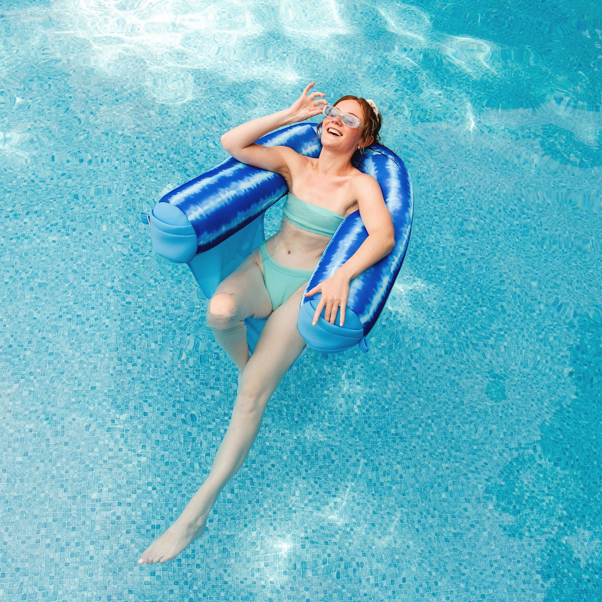 Woman relaxing on a blue inflatable ring in a pool