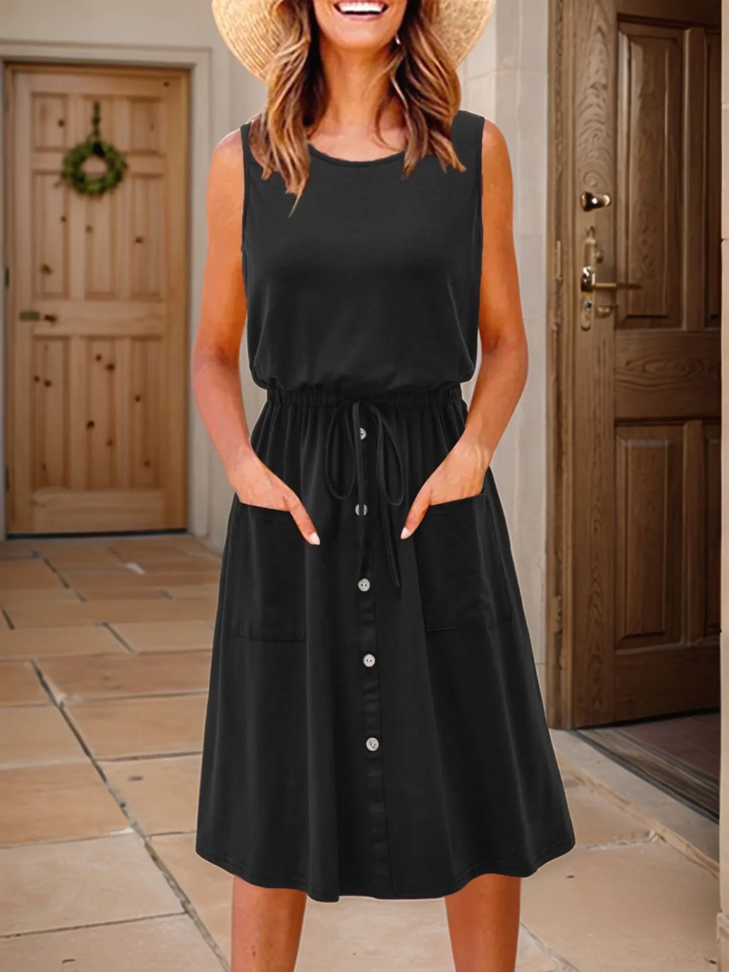 A model wearing a red sleeveless knee-length dress with a round neckline, drawstring waist, and front pockets.