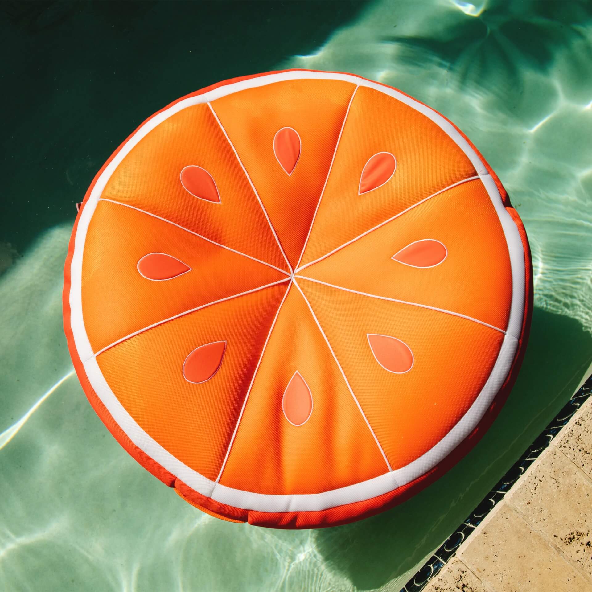 Inflatable pool float shaped like an orange slice on a pool