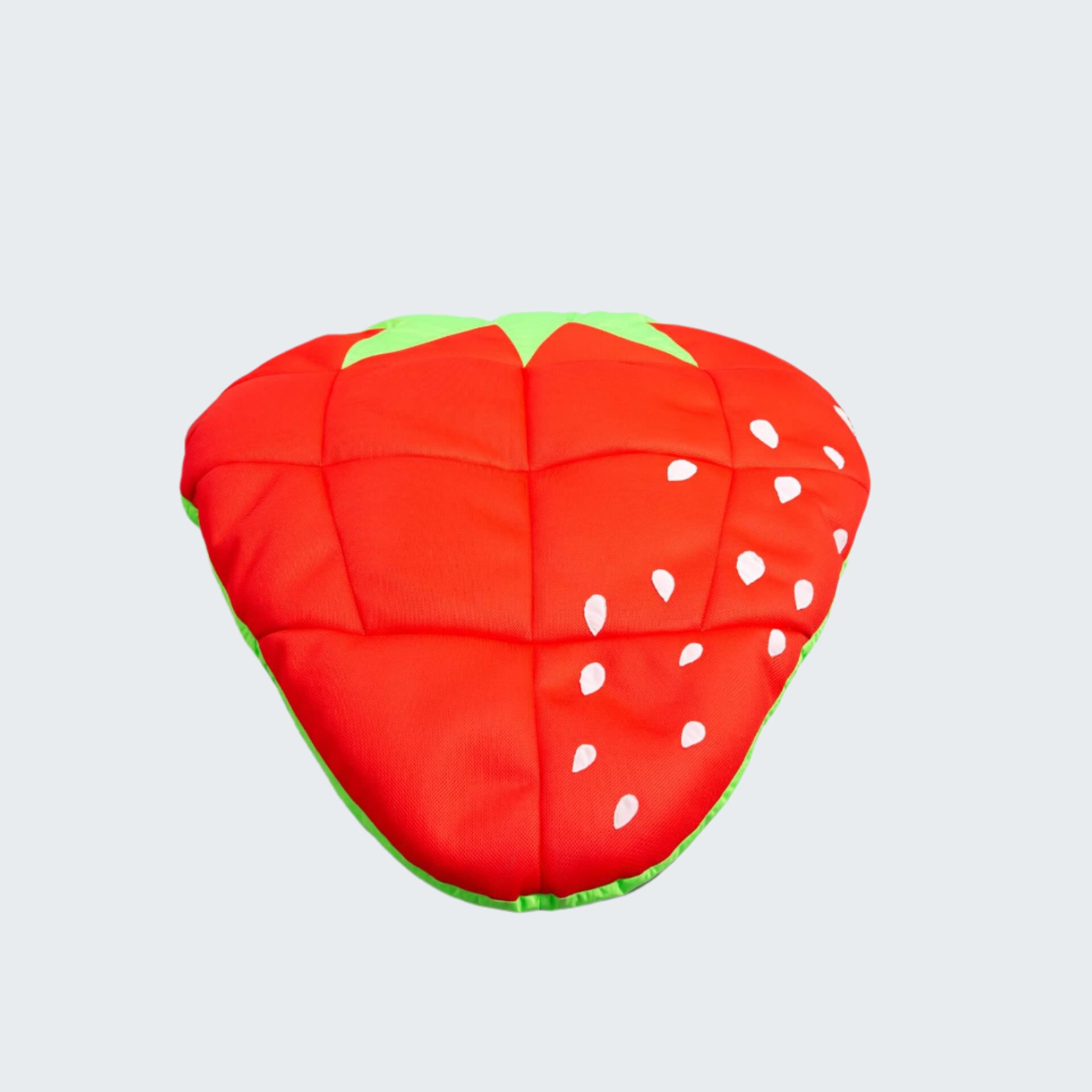Strawberry-shaped cushion with red body, green leaves, and white seeds on a white background