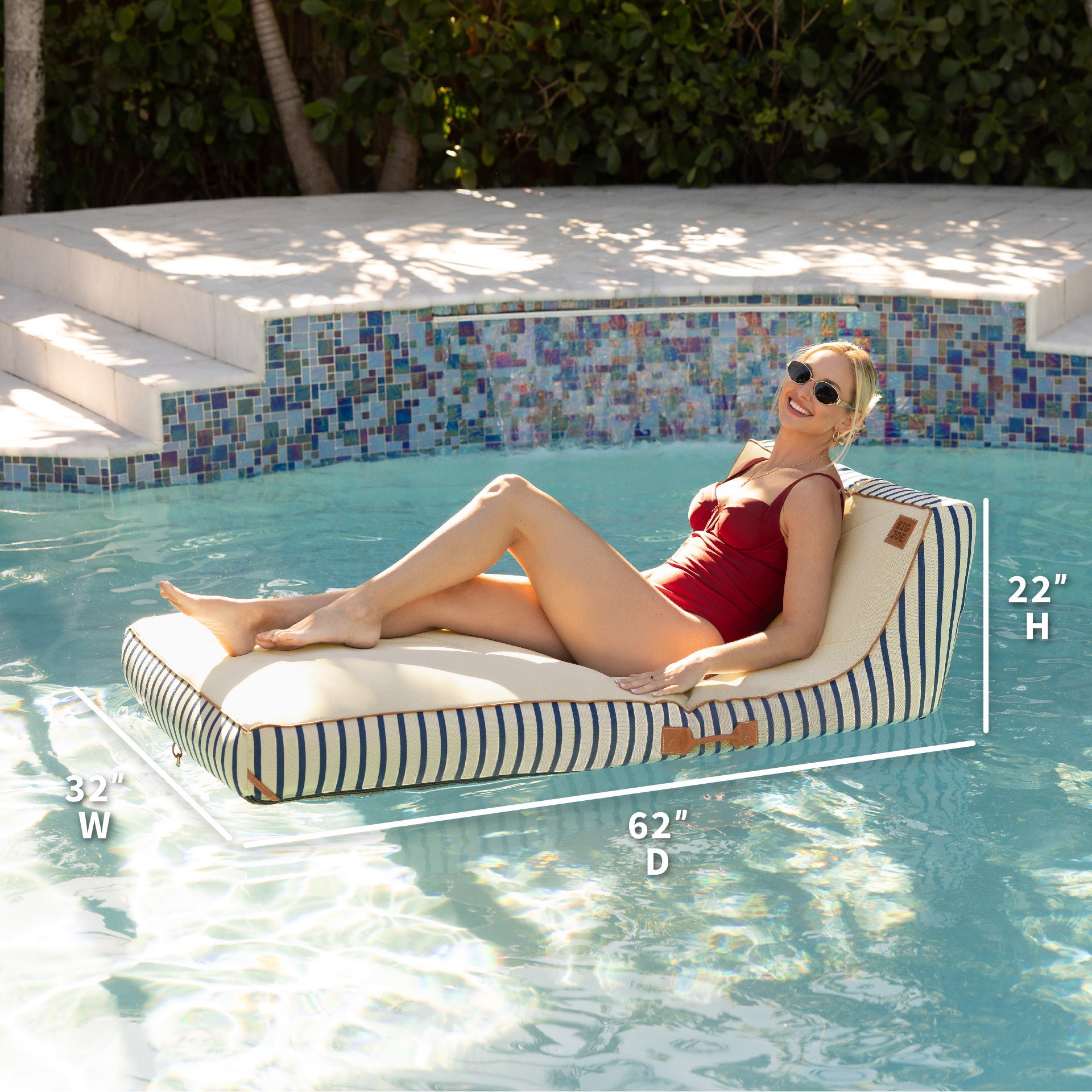 Woman lounging on a striped pool float with measurements displayed, set against a poolside background.