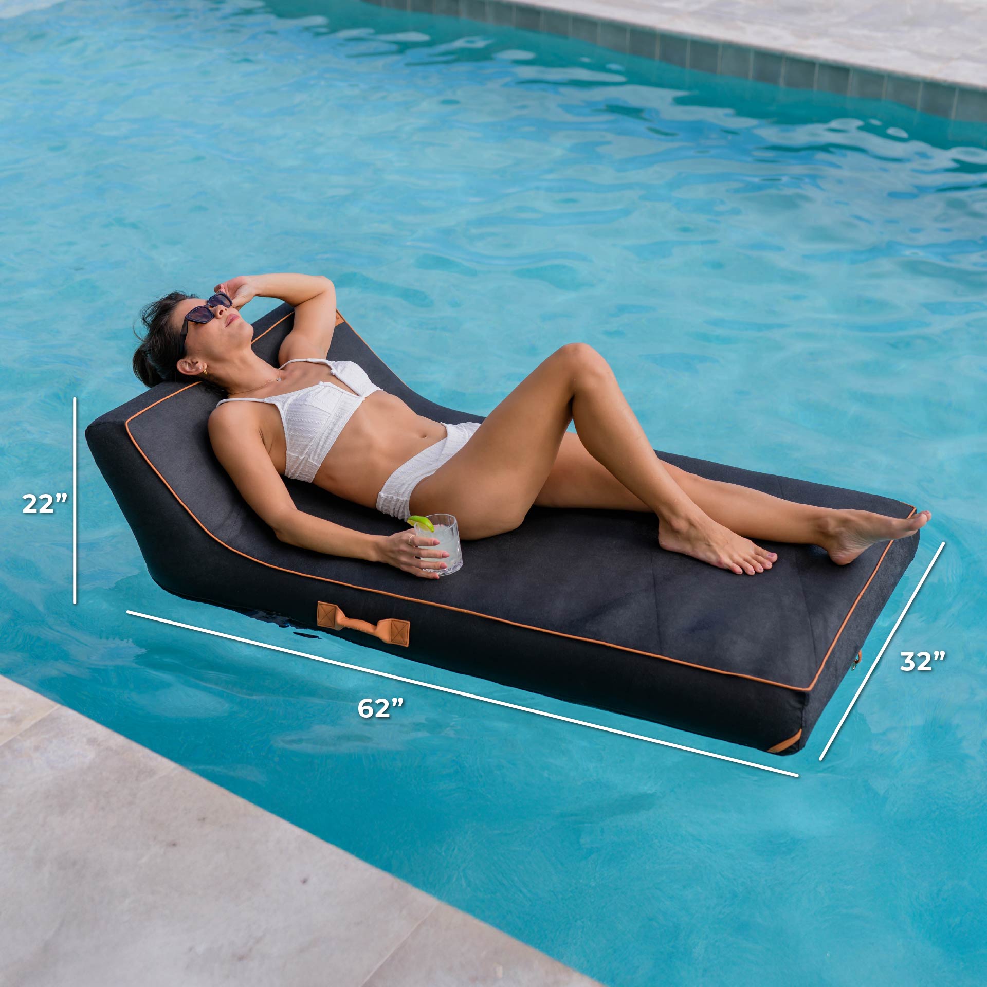 Woman lying on a black pool float with measurements, by a pool.