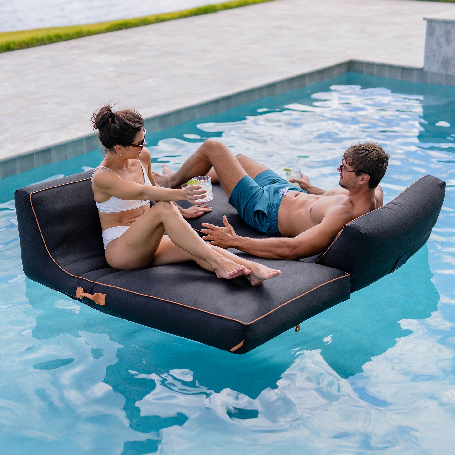 Two people relaxing on a floating lounge in a pool