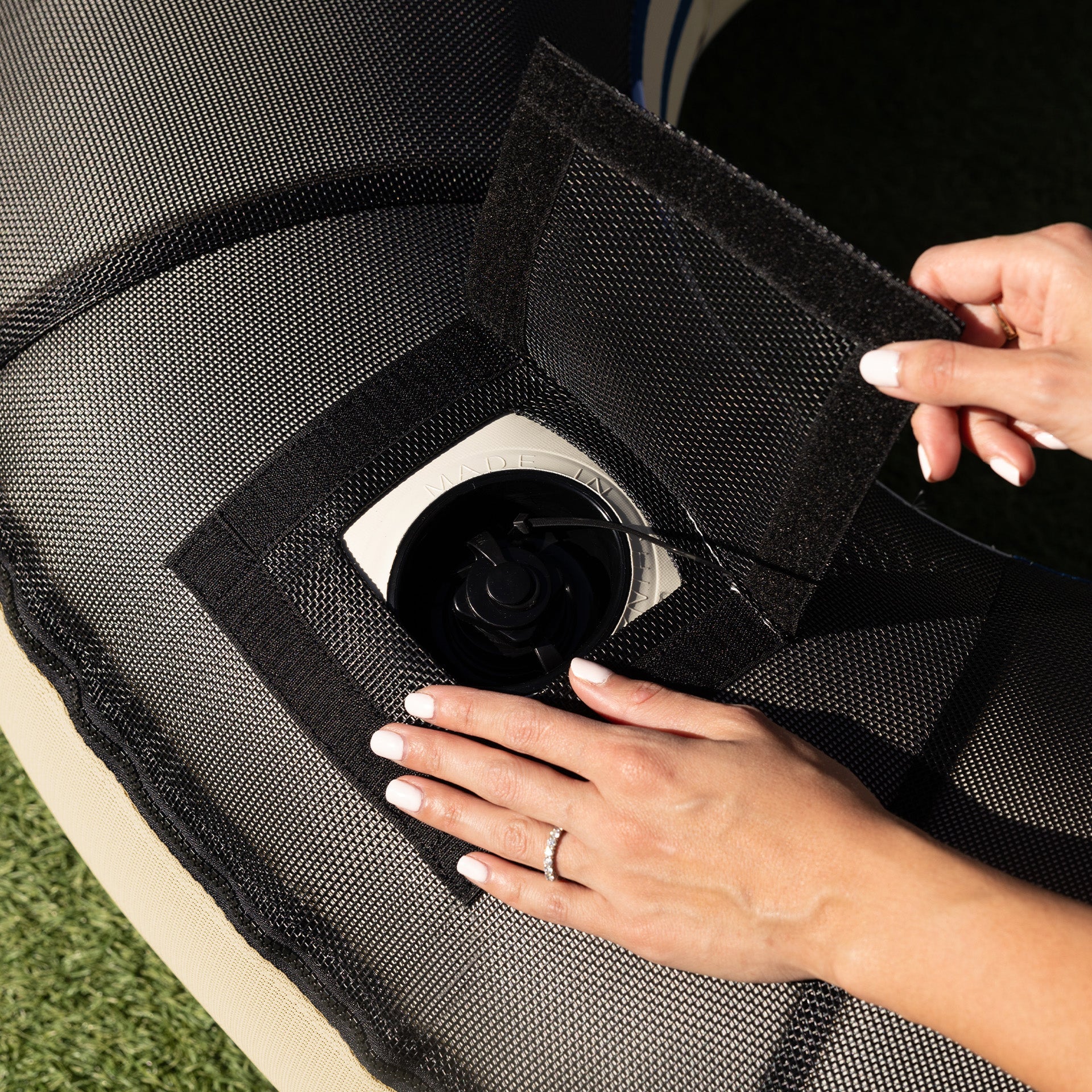 Person adjusting a black car seat cover with a camera lens visible.