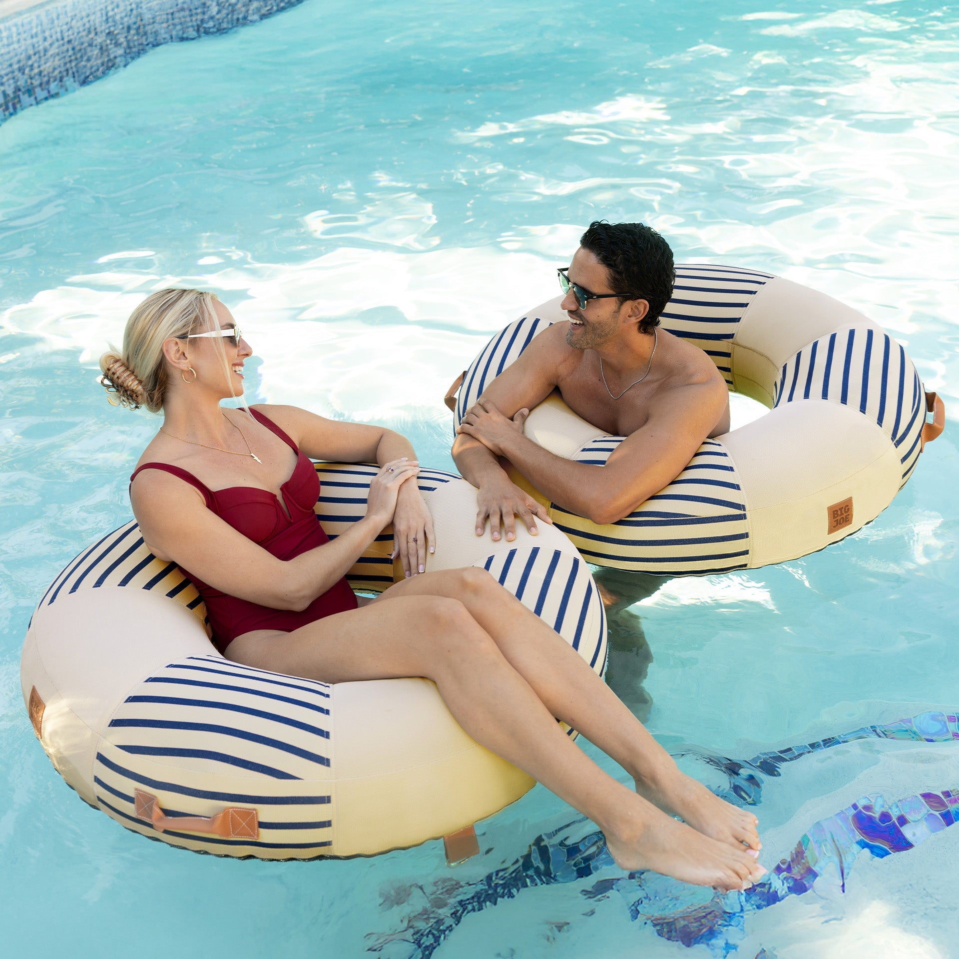 Two people on striped pool floats in a swimming pool