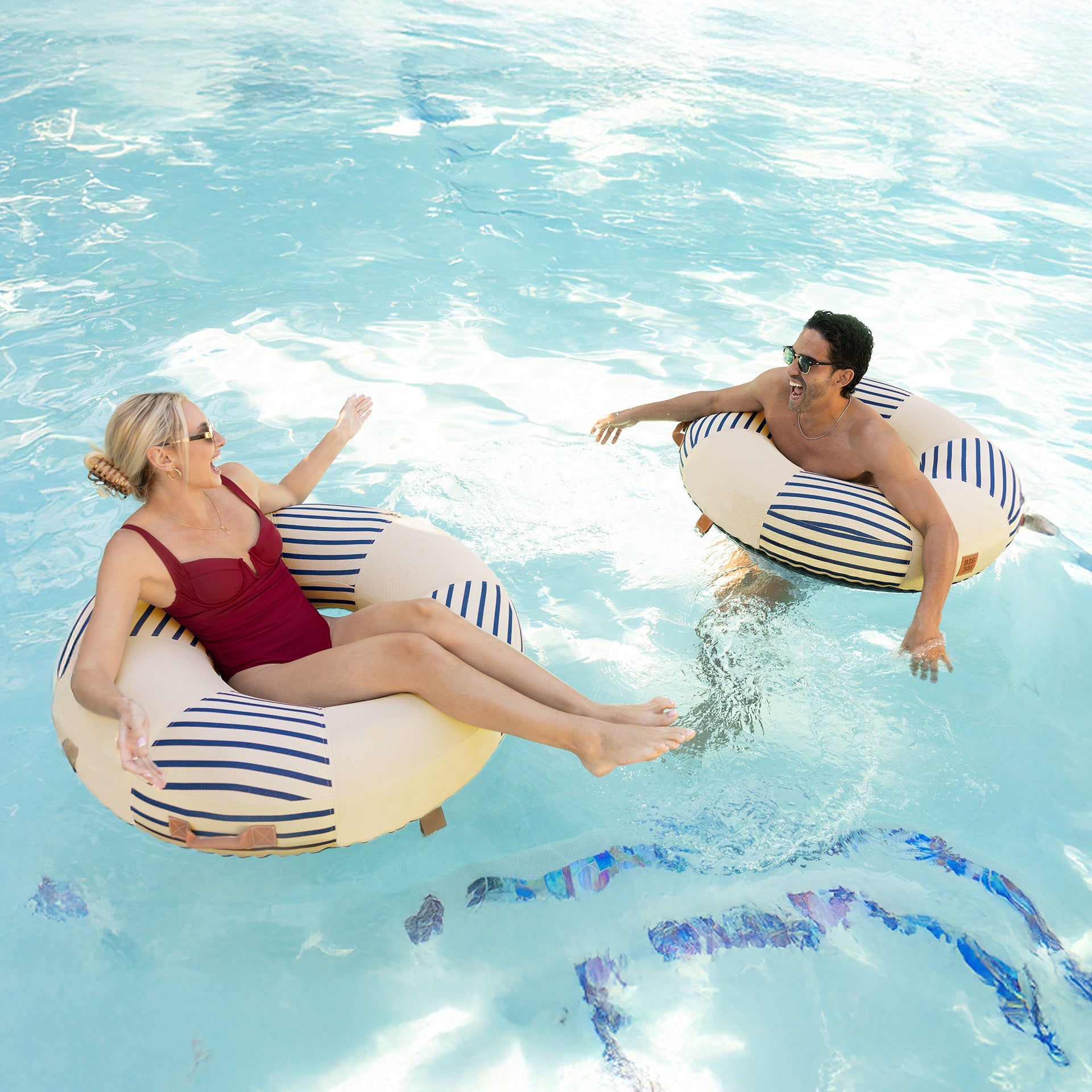 Two people on striped inner tubes in a pool