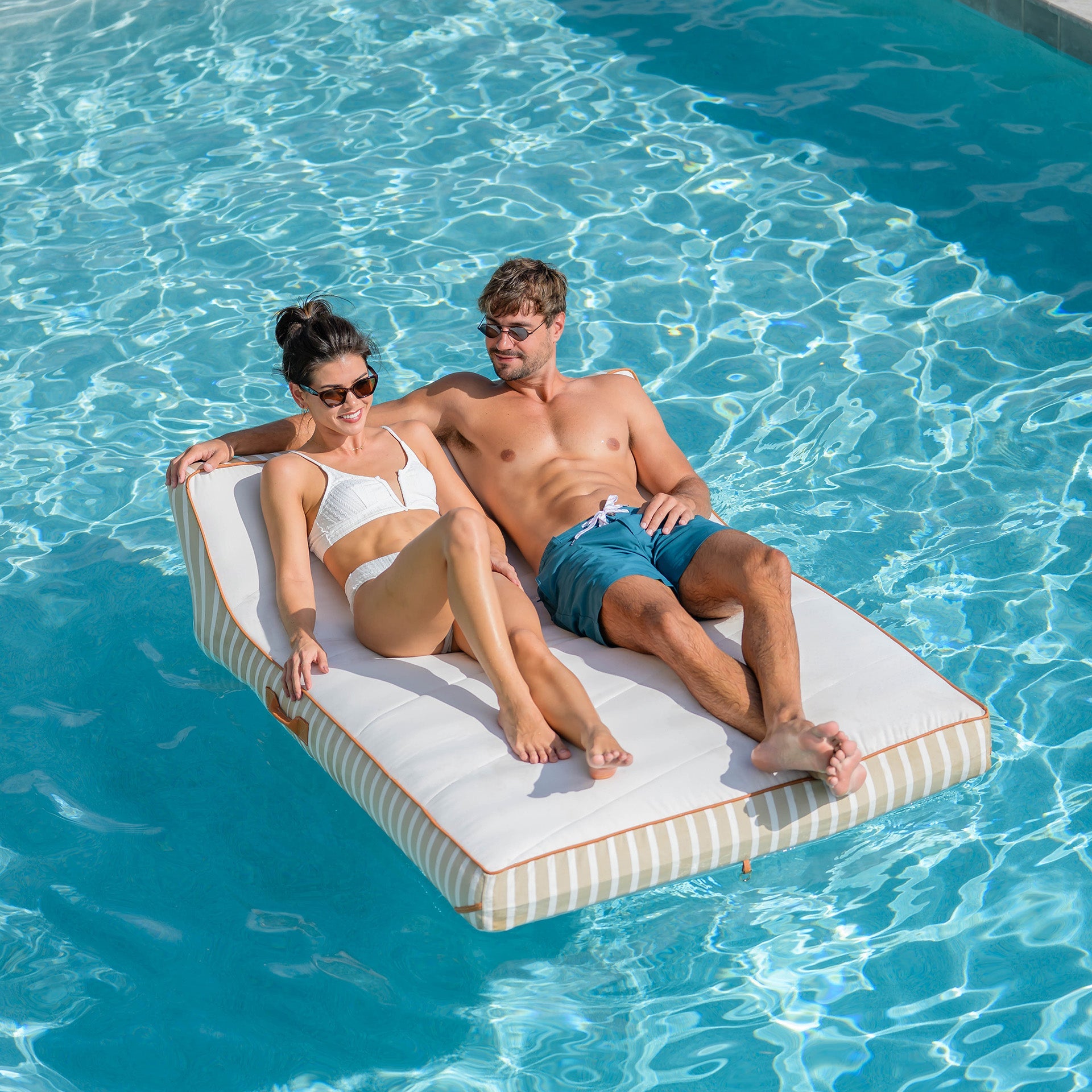 Two people relaxing on a floating platform in a pool