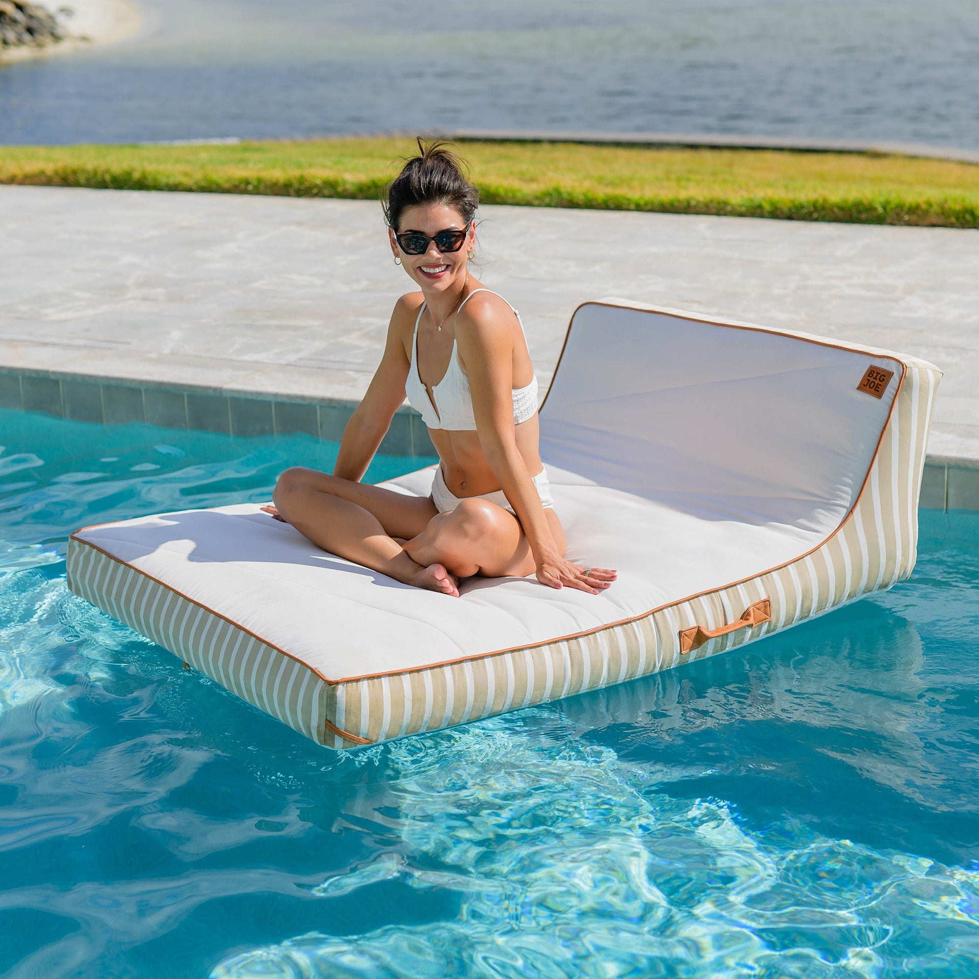 Woman sitting on a floating lounge in a pool with sunglasses on