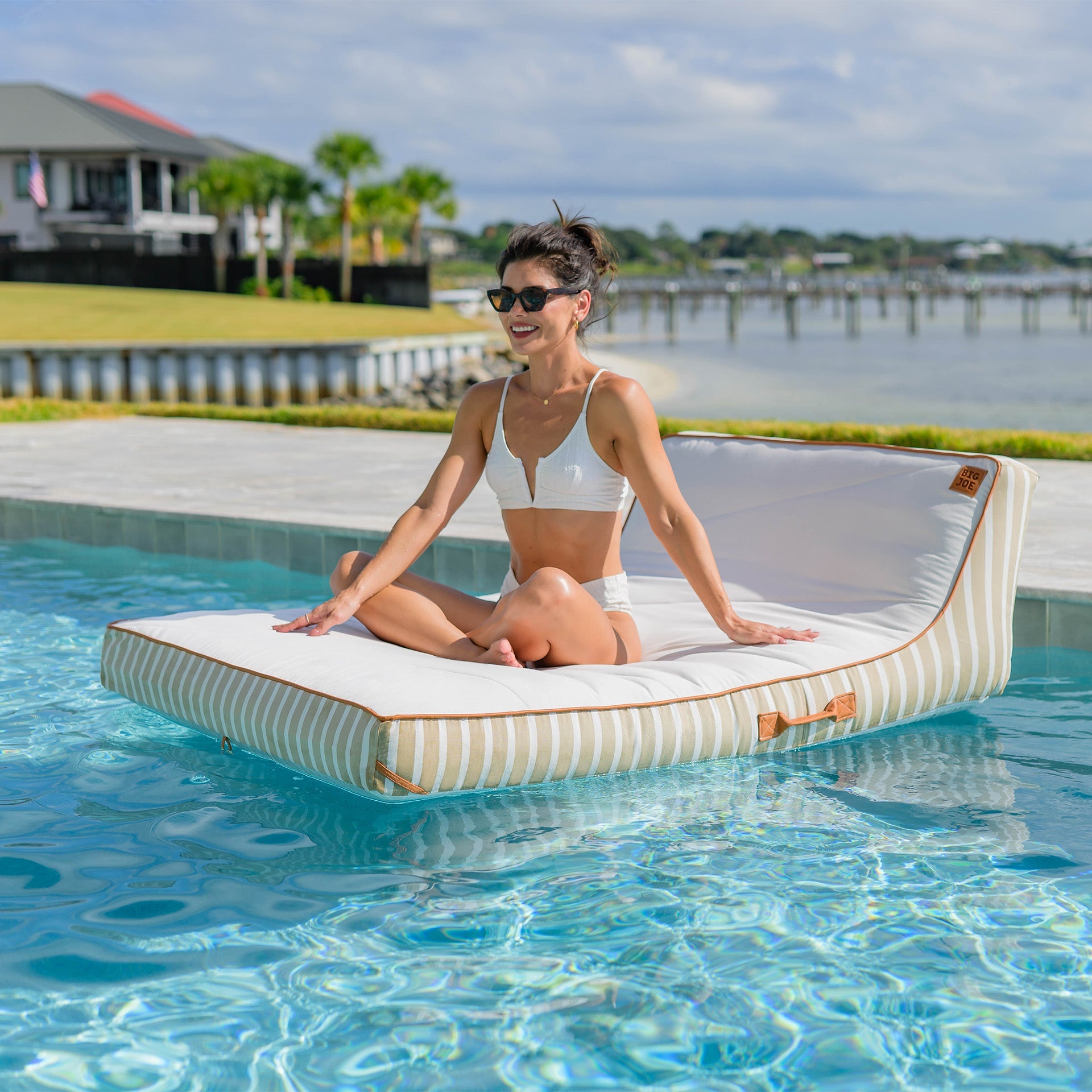 Woman sitting on a floating platform in a pool with a scenic background