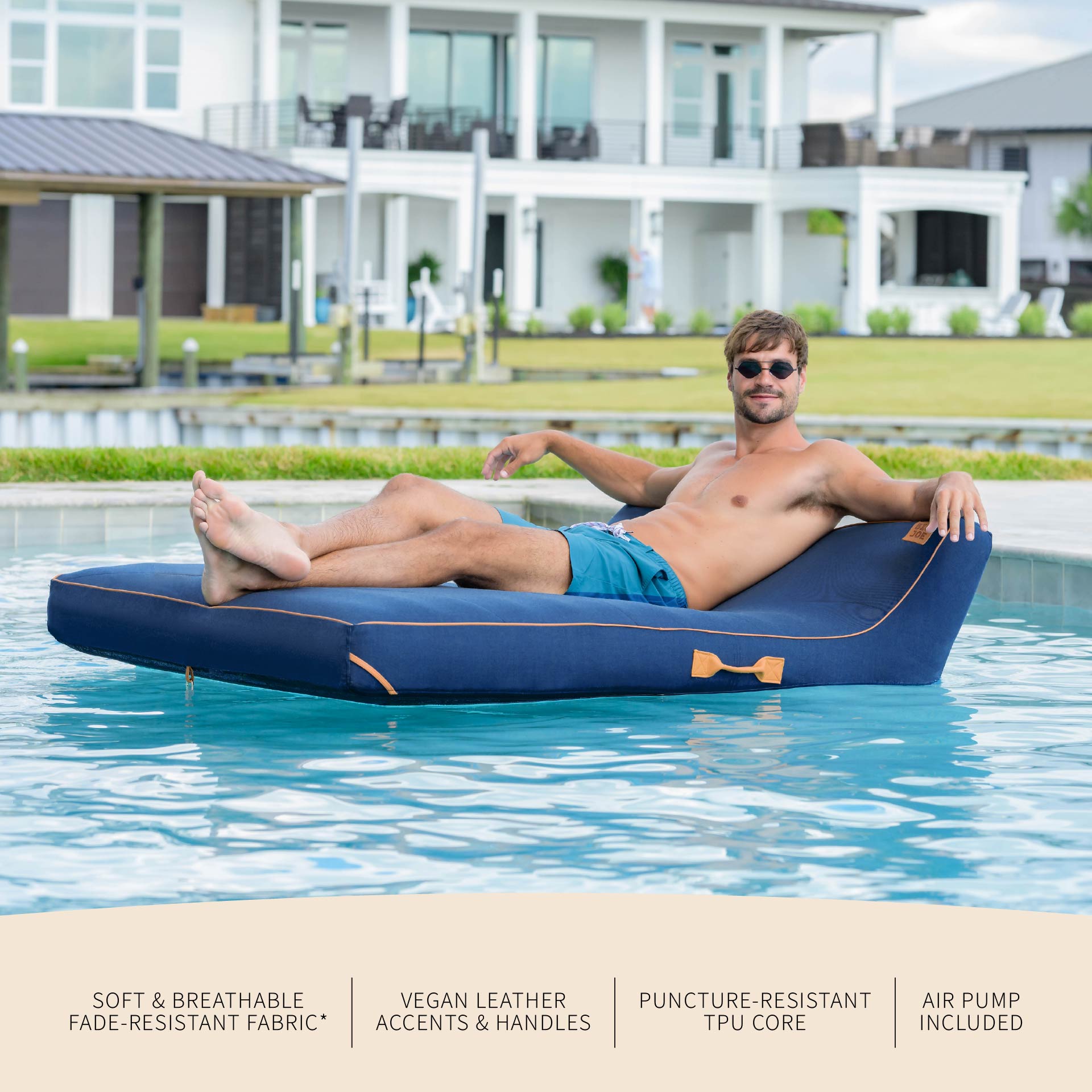 Man lounging on a blue inflatable pool float in a swimming pool with a house in the background.
