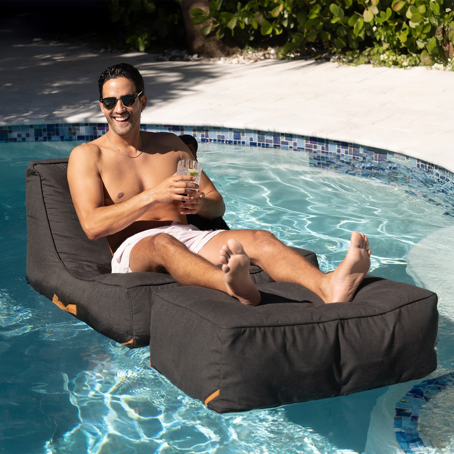 Man lounging on a floating bean bag by a pool