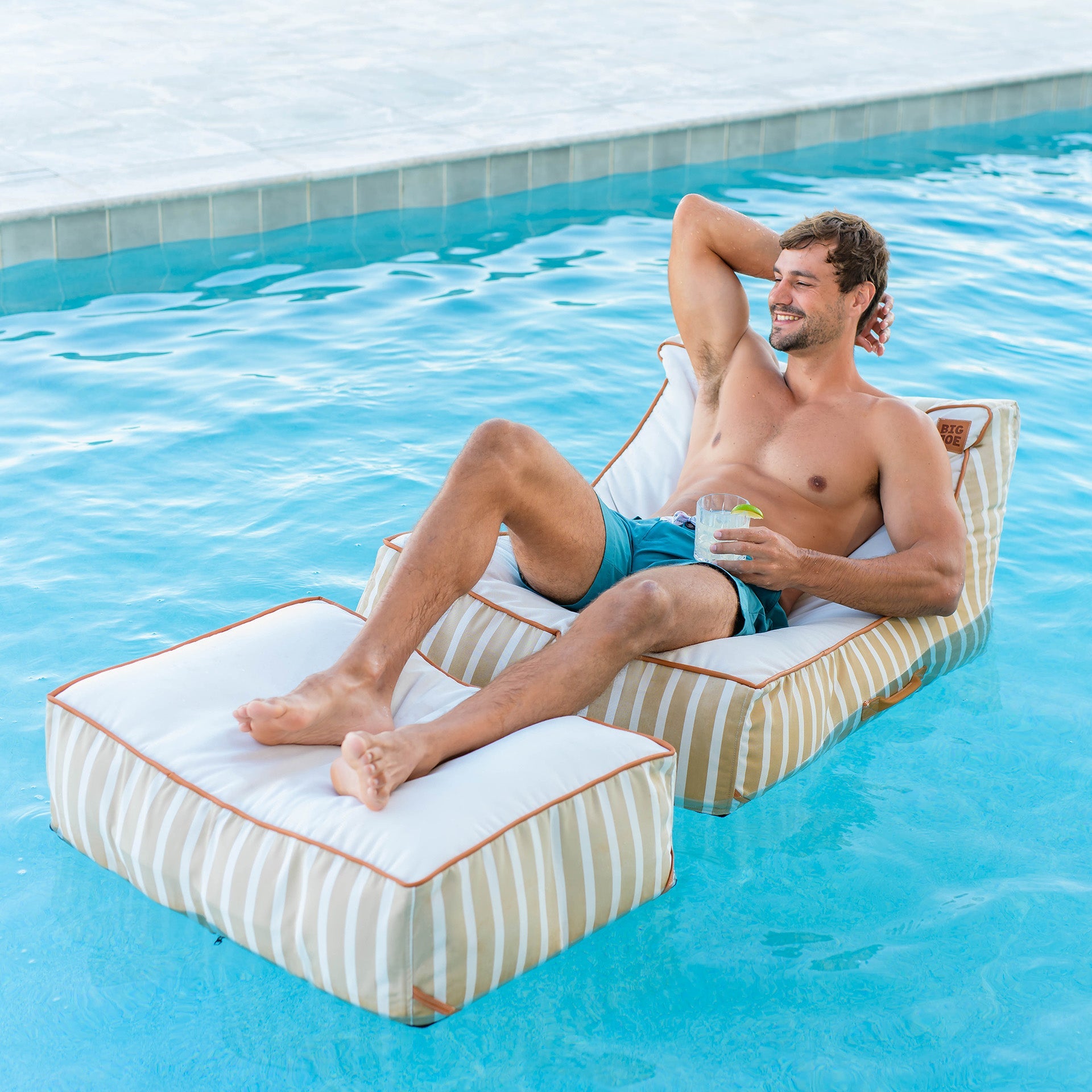 Man relaxing on a striped pool float in a swimming pool