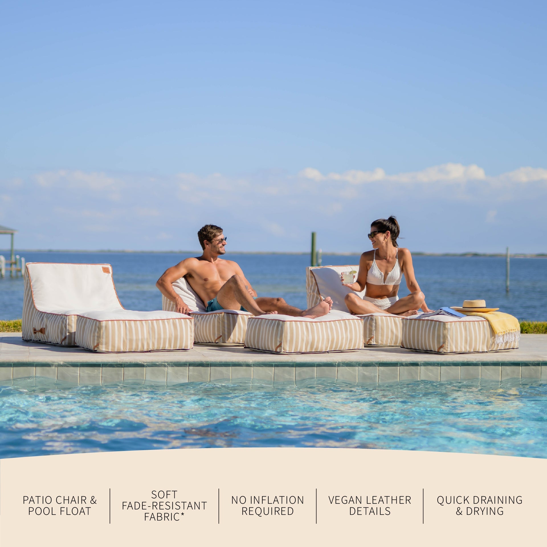 Two people sitting on patio chairs by a pool with ocean view
