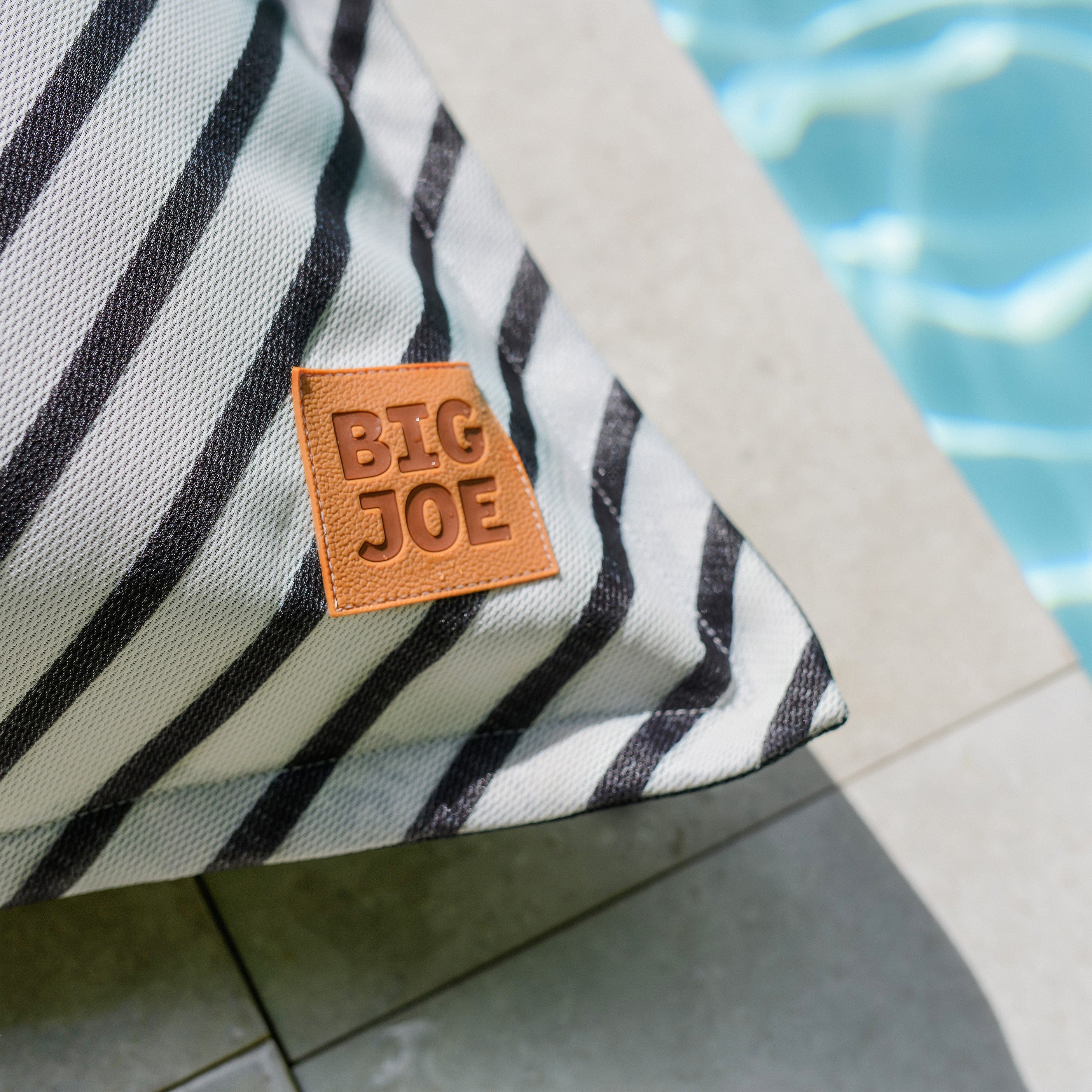 Striped towel with a 'BIG JOE' label by a pool