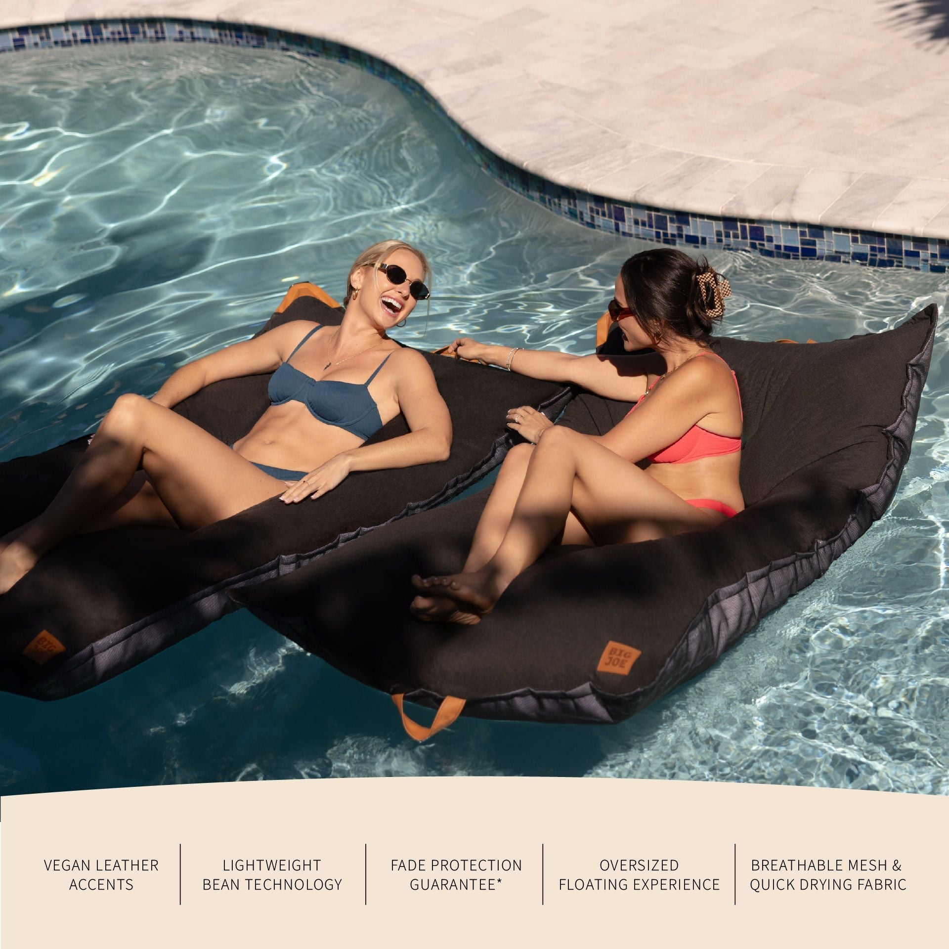 Two people lounging on a black inflatable bean bag in a pool.