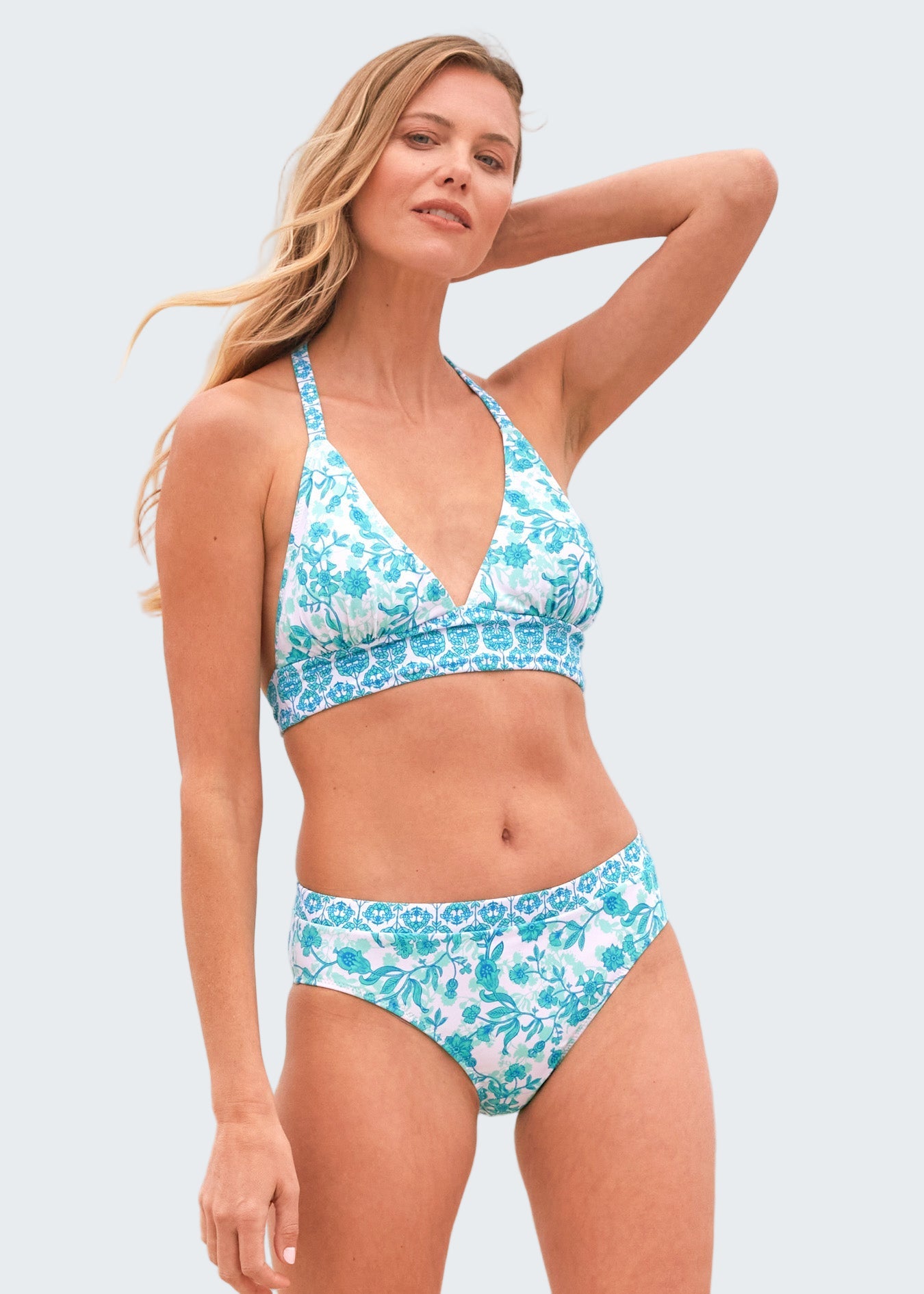 Woman wearing a blue floral bikini set with a beach background