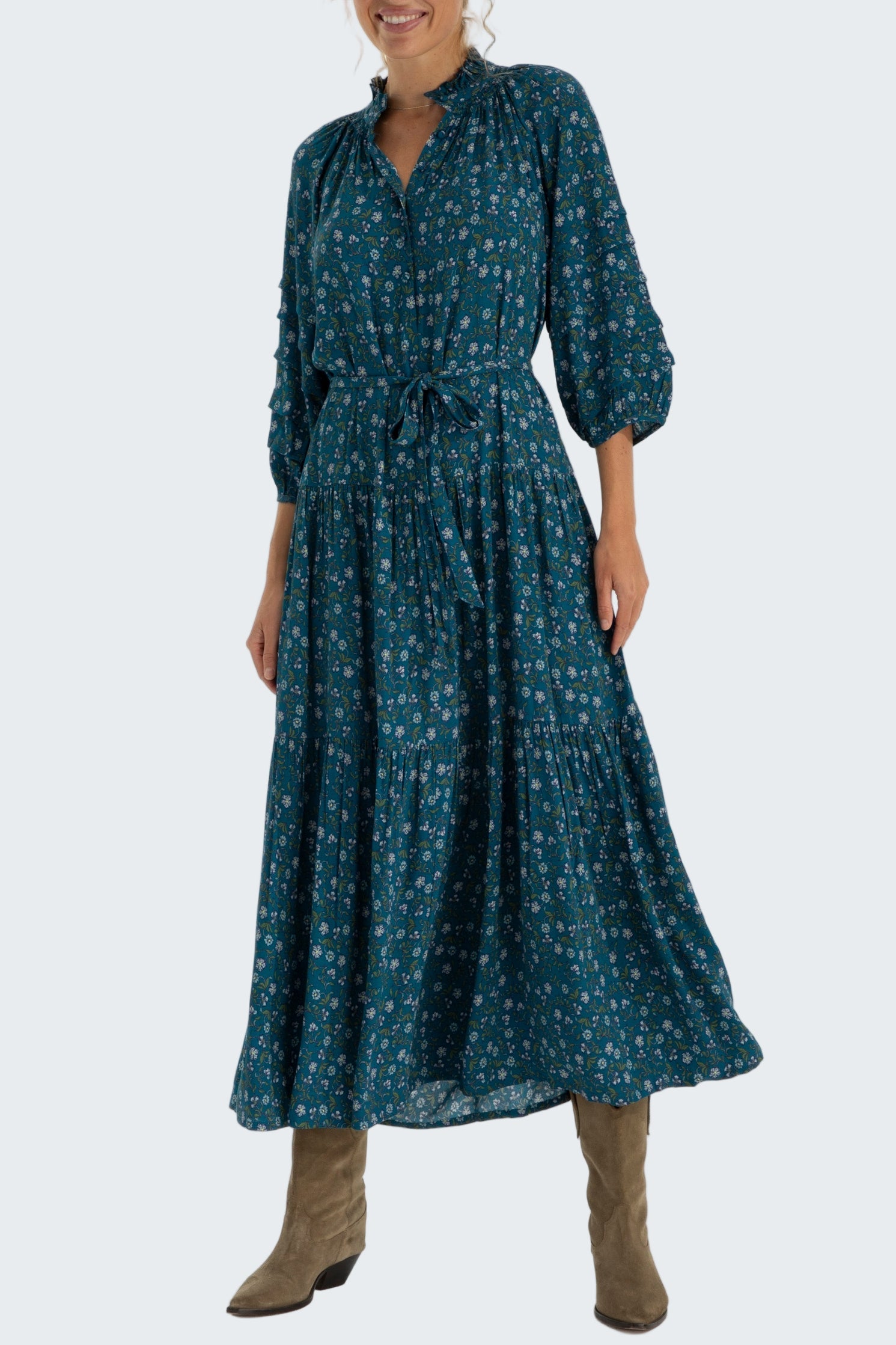 Woman wearing a long teal dress with a pattern on a white background