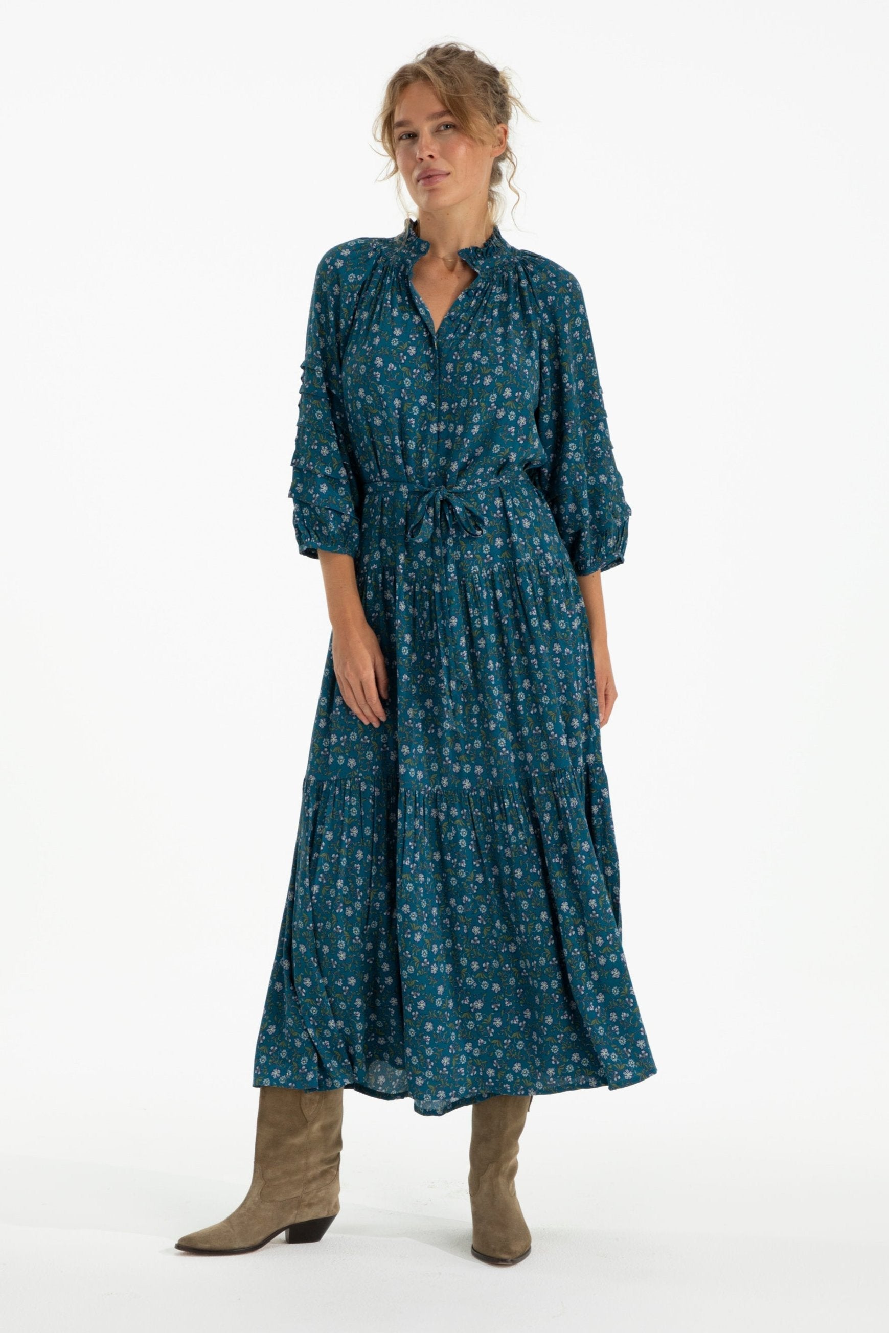 Woman wearing a teal patterned dress on a white background