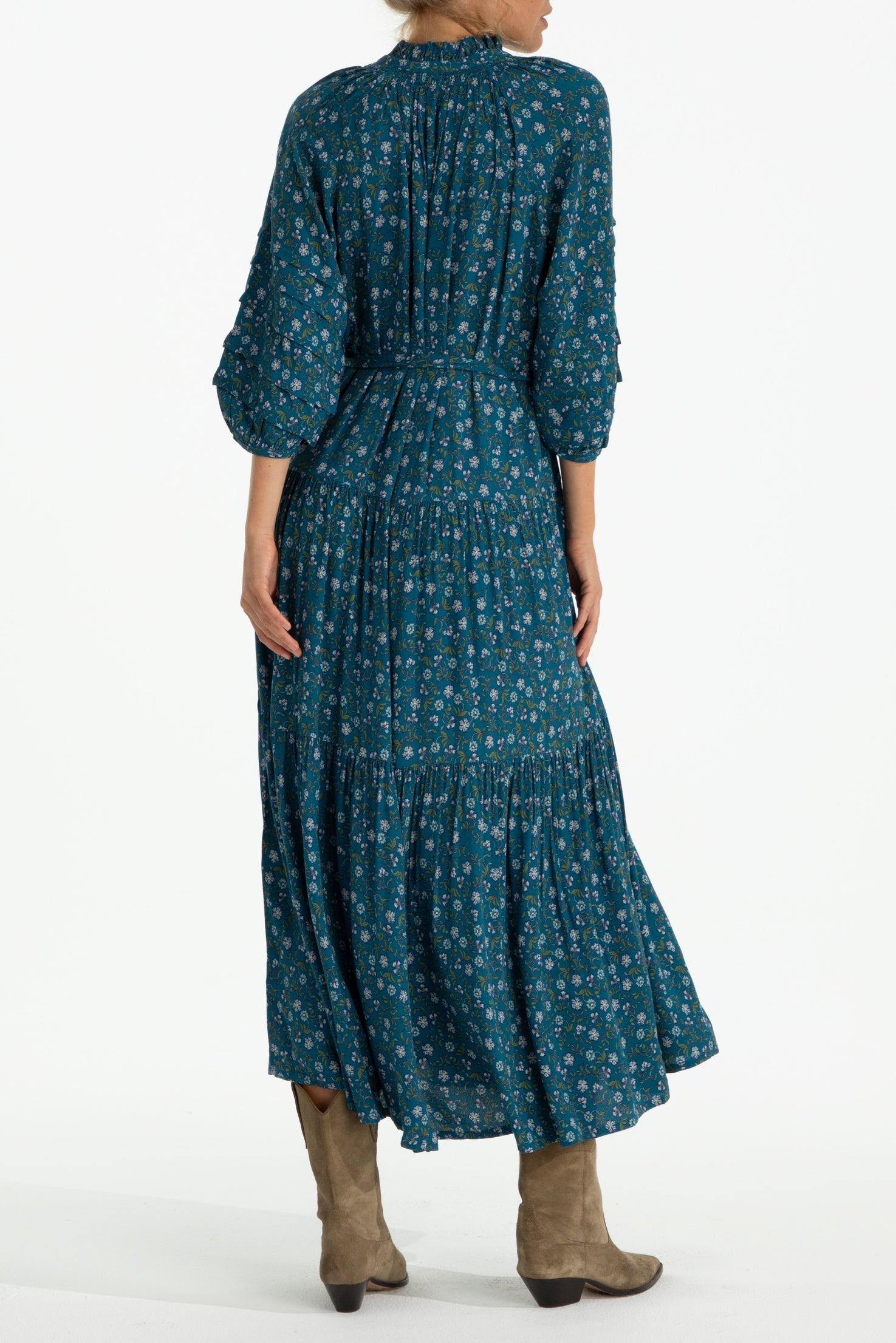 Woman wearing a teal patterned dress with long sleeves on a white background