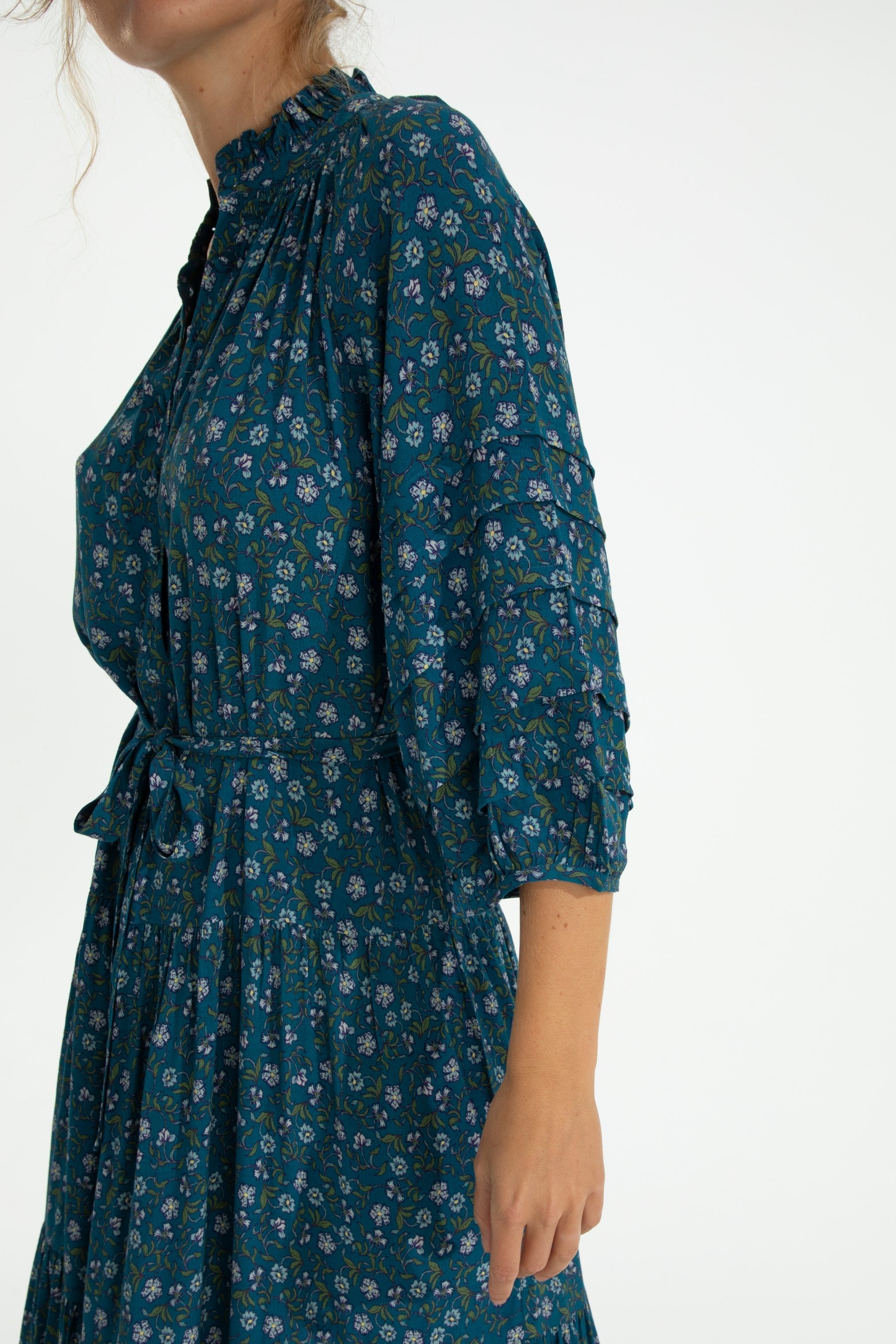 Teal floral dress worn by a person on a white background