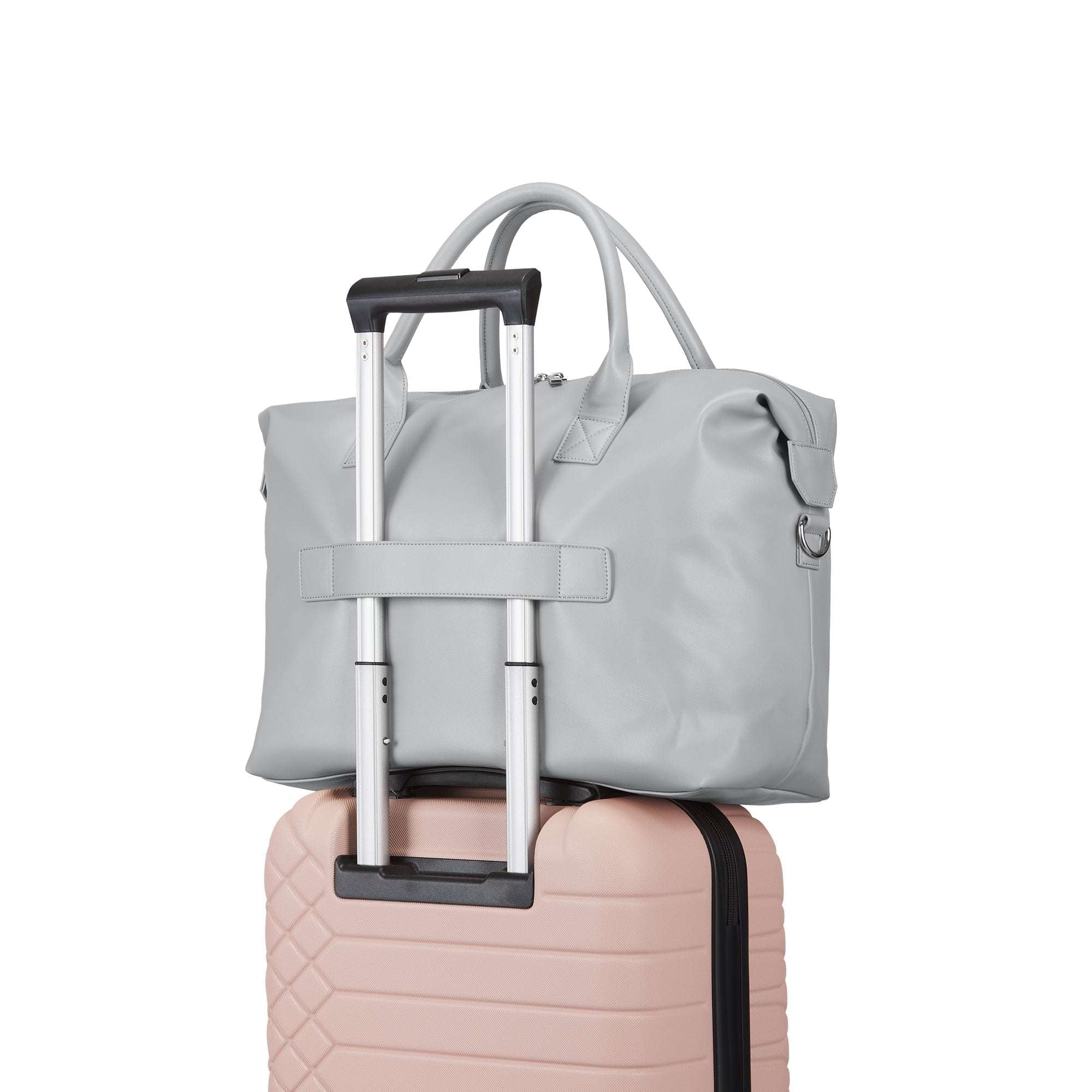Light gray bag with a handle attached to a pink suitcase on a white background