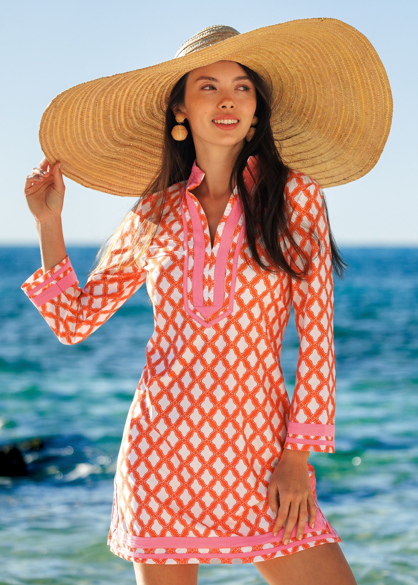 Woman wearing a patterned dress and large sun hat on a beach
