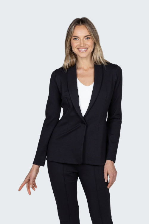 Woman wearing a black suit jacket and pants on a gray background