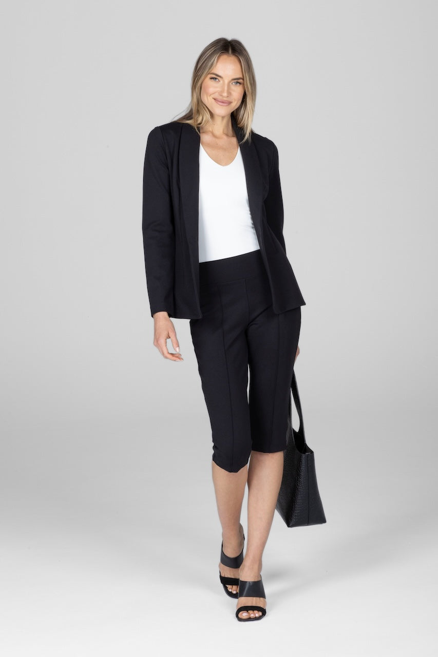 Woman wearing a black blazer and black pants on a white background