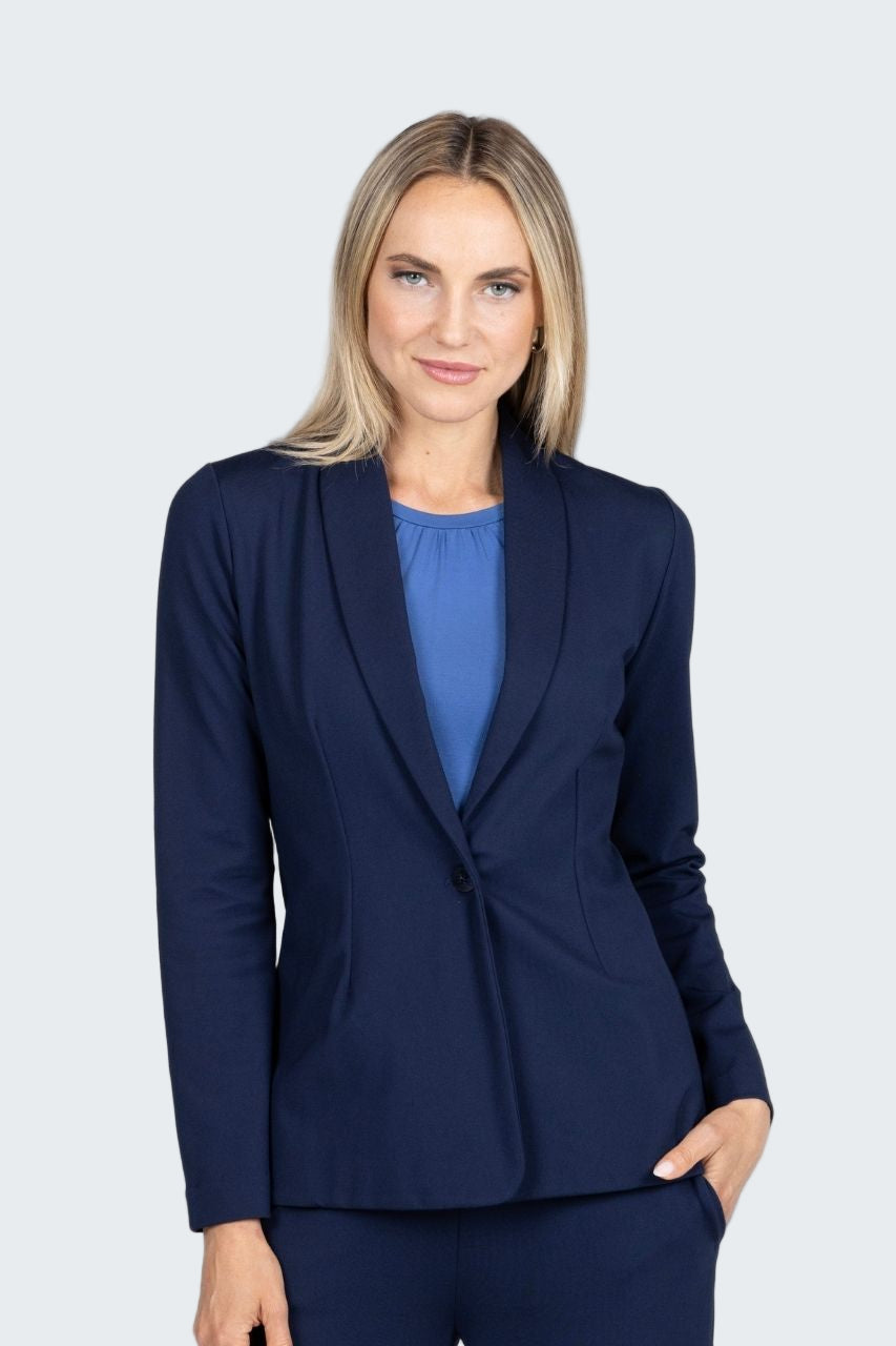 Woman wearing a navy blazer over a blue top on a gray background