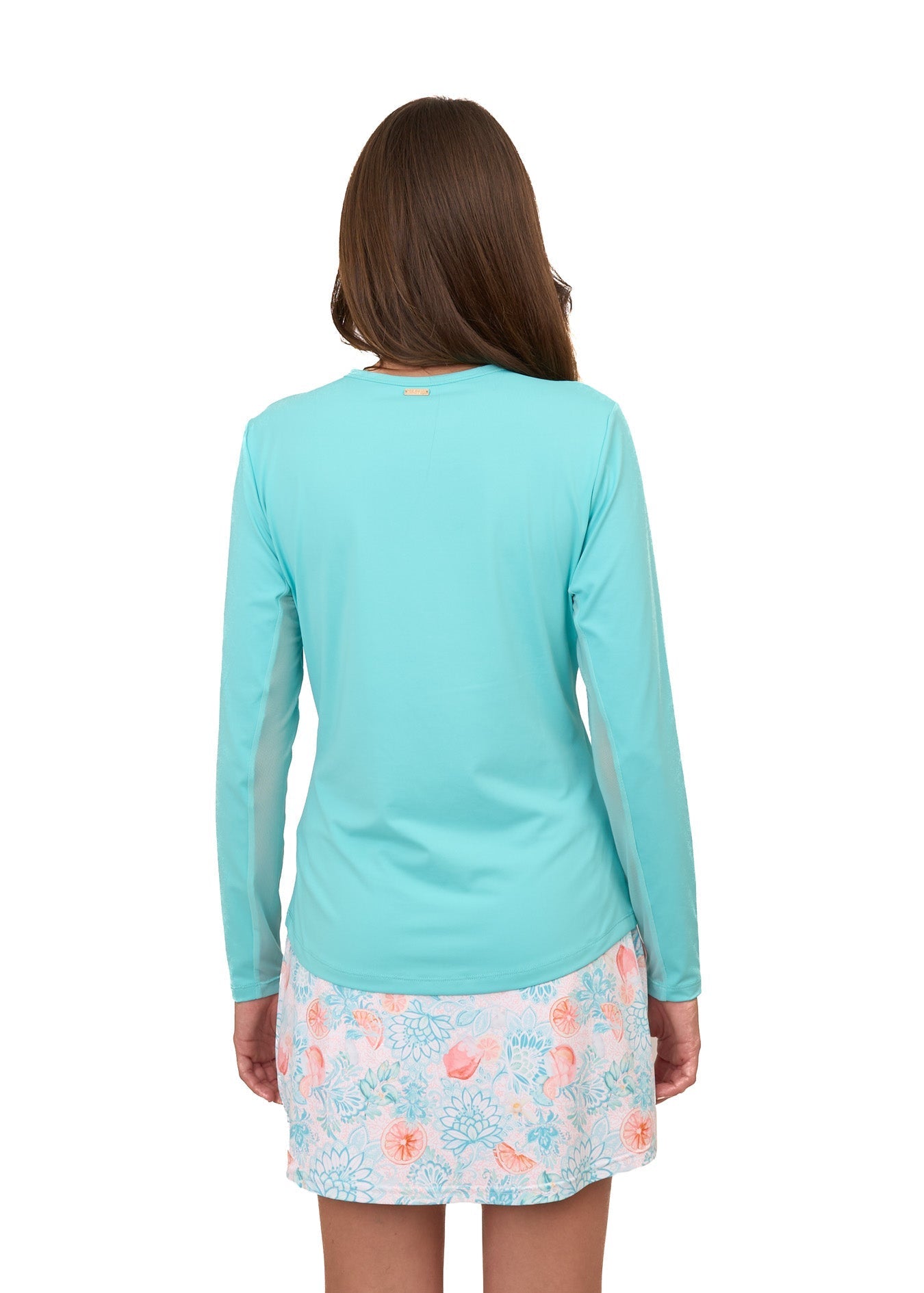 Girl wearing a turquoise long-sleeve shirt and floral skirt on a white background