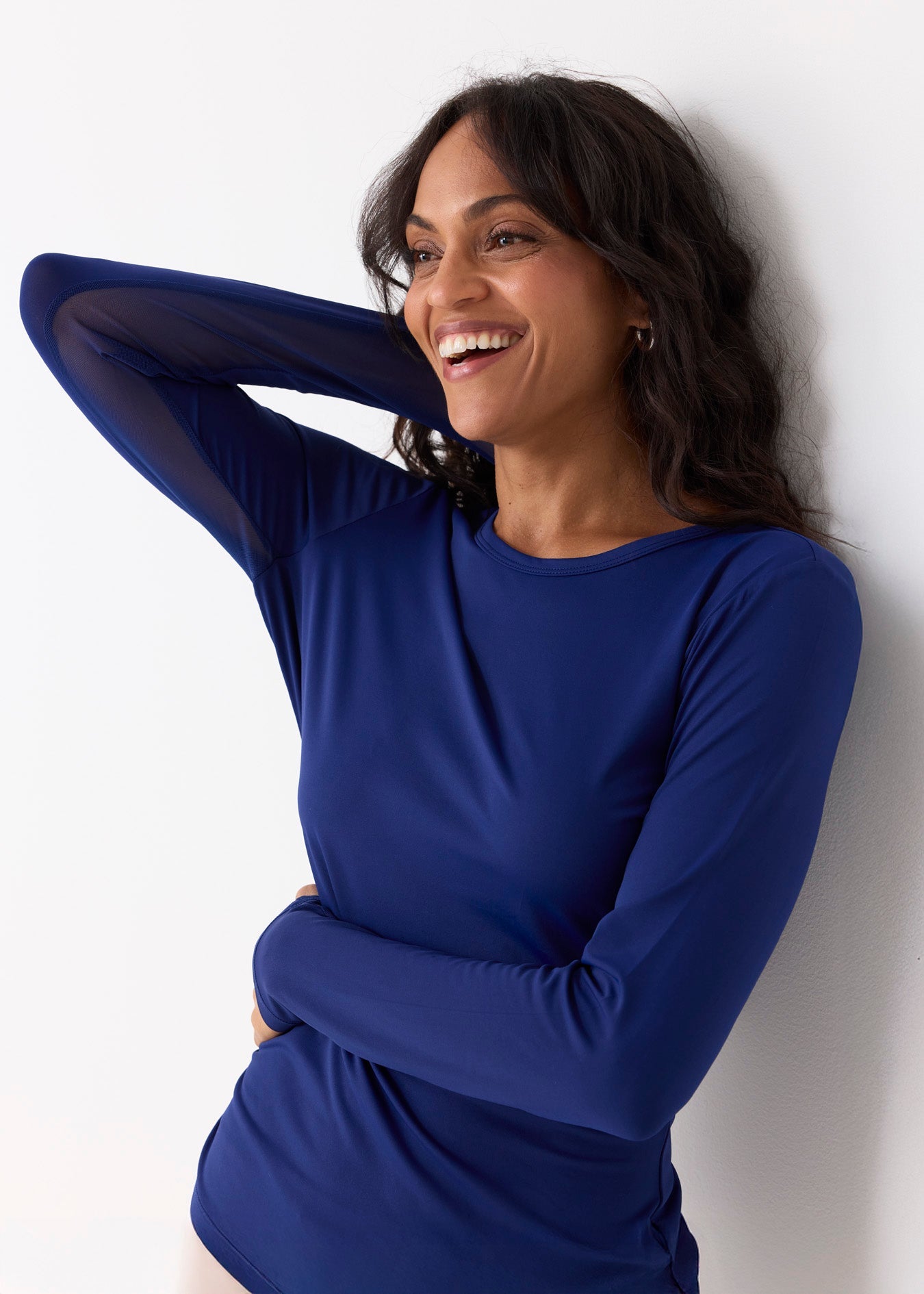 Woman wearing a blue long-sleeve top against a white background