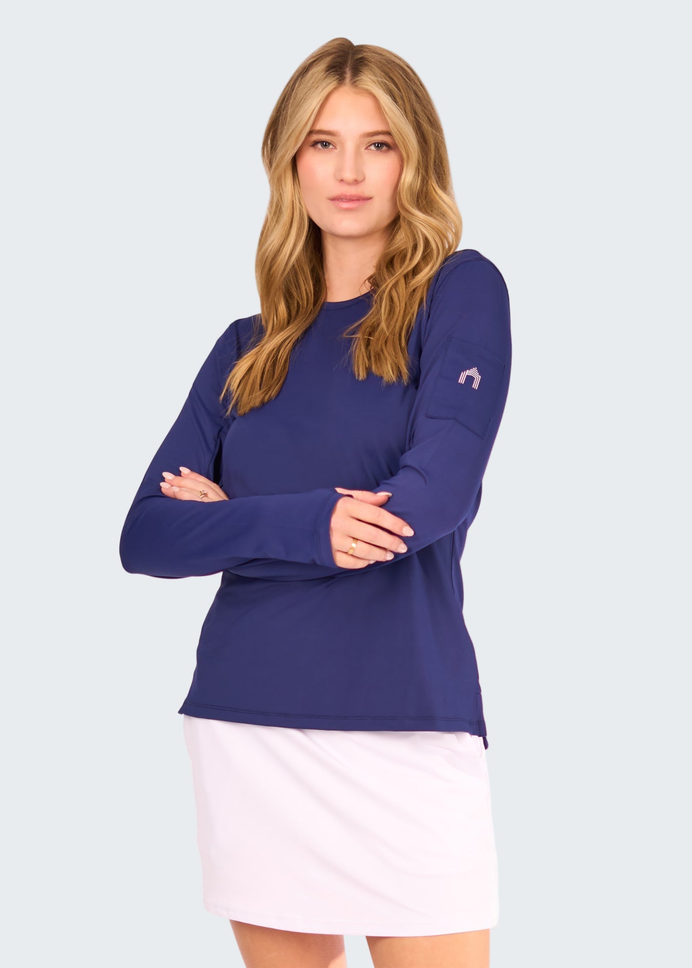 Woman wearing a blue long-sleeve top and white skirt on a white background