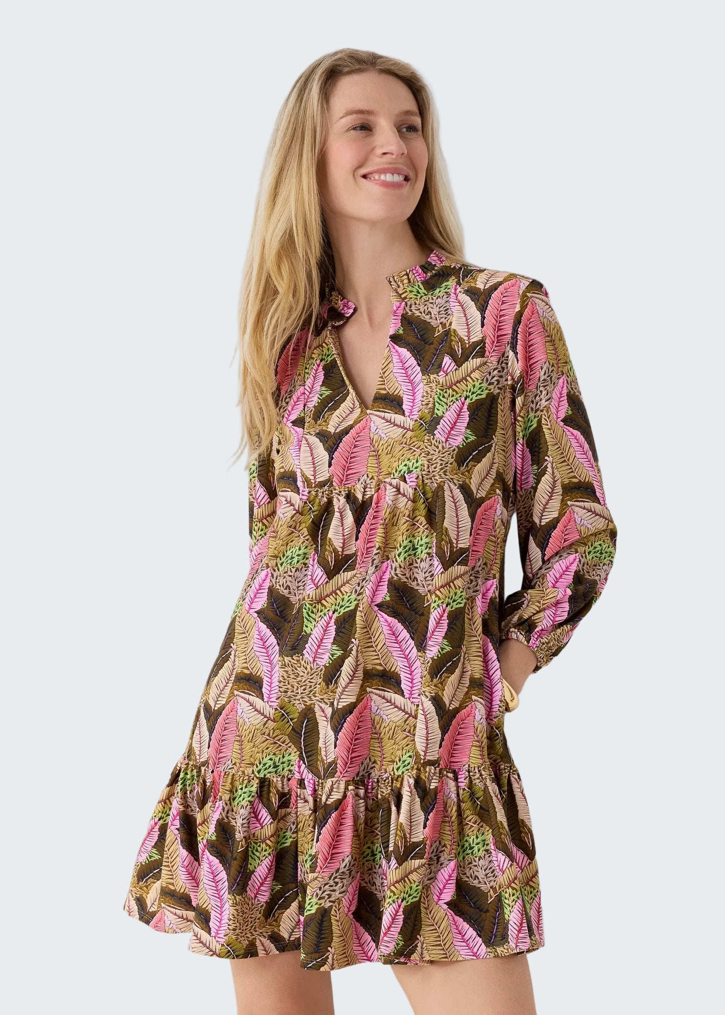 Woman wearing a patterned dress with long sleeves on a plain background