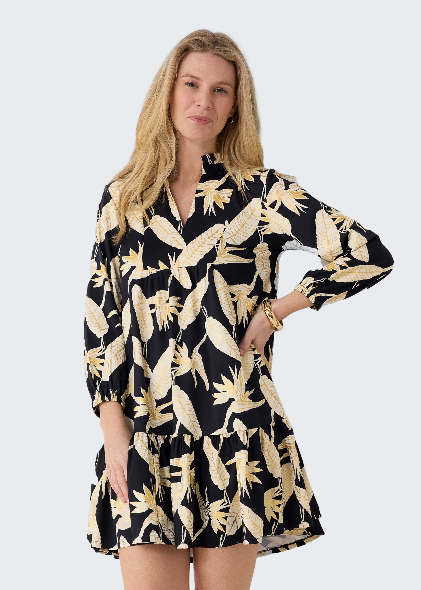 Woman wearing a black dress with gold floral pattern against a white background