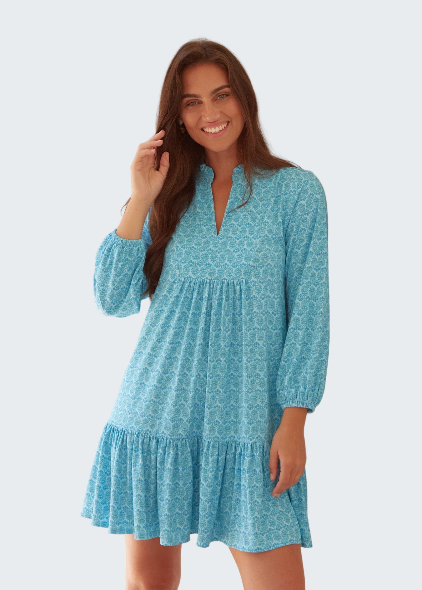 Woman wearing a blue patterned dress against a light background