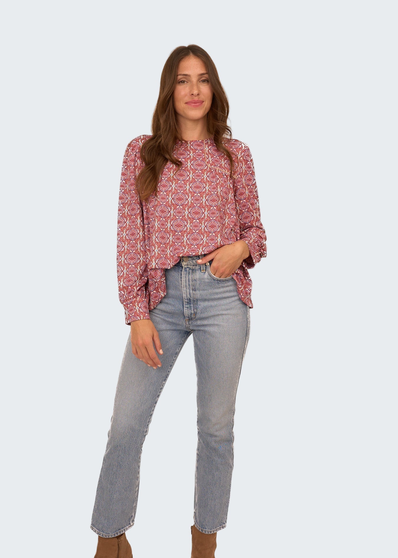 Woman wearing a patterned blouse and jeans on a white background