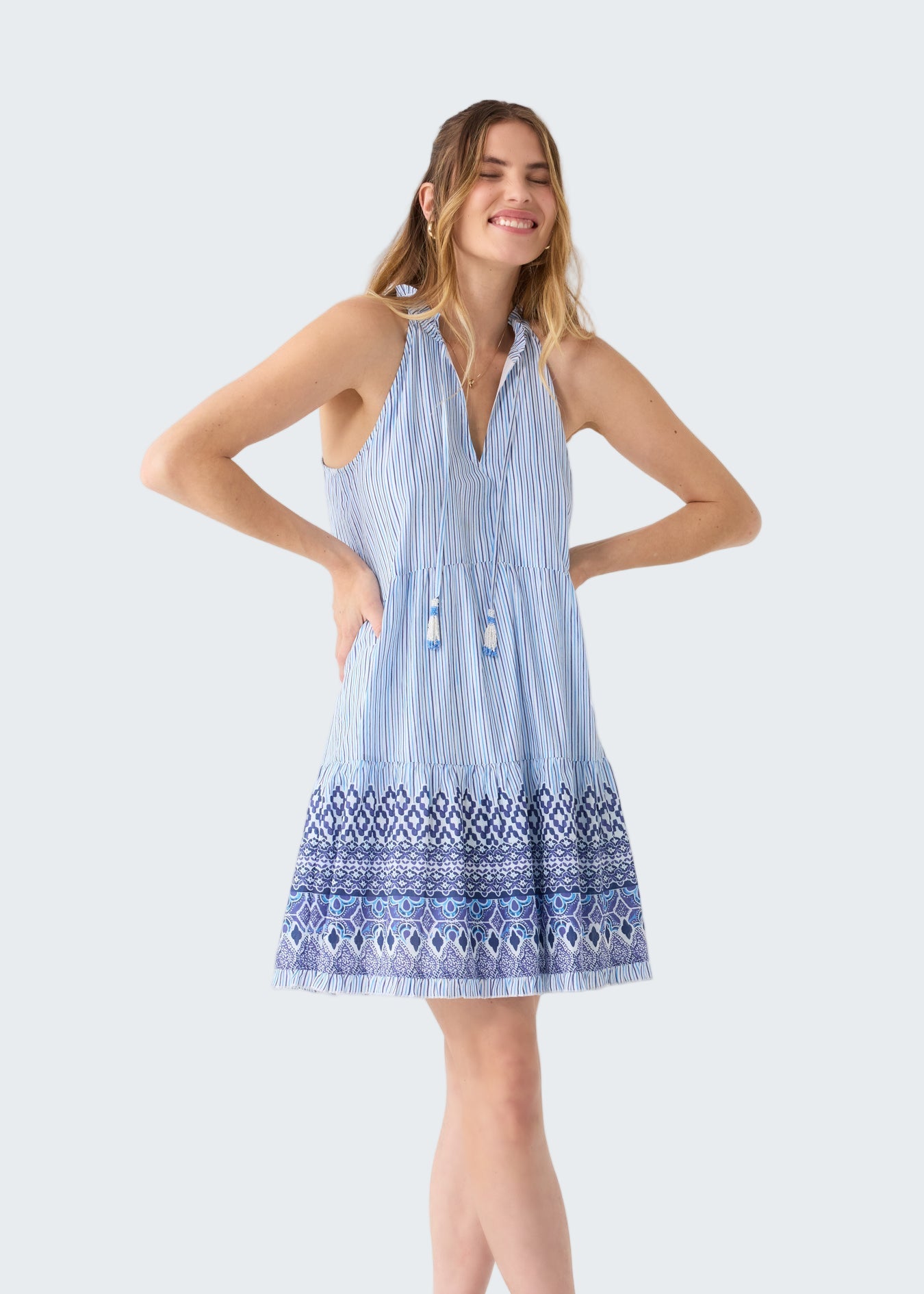 Woman wearing a blue and white striped dress with a geometric hem on a white background