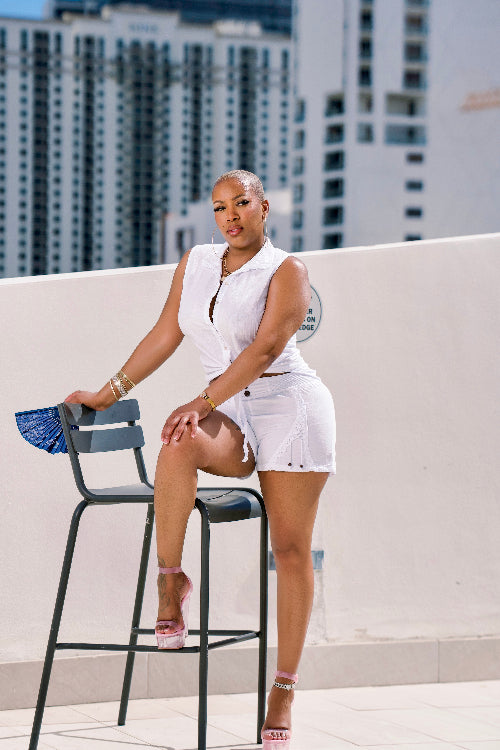 Woman in a white outfit sitting on a chair with cityscape in the background