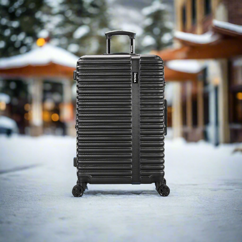 Black suitcase on wheels in a snowy outdoor setting with blurred background