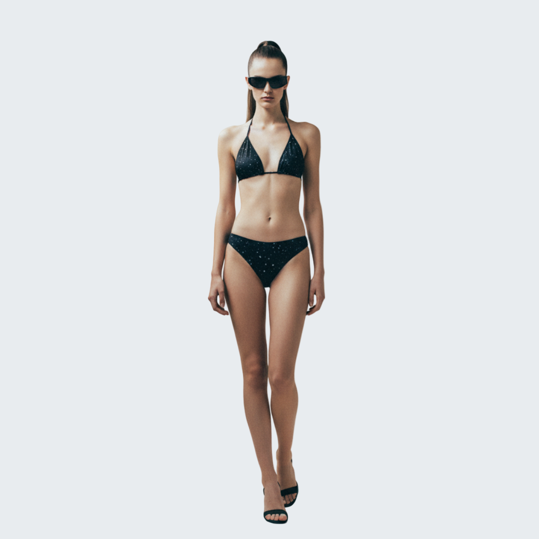 Woman wearing a black bikini and sunglasses against a beige background