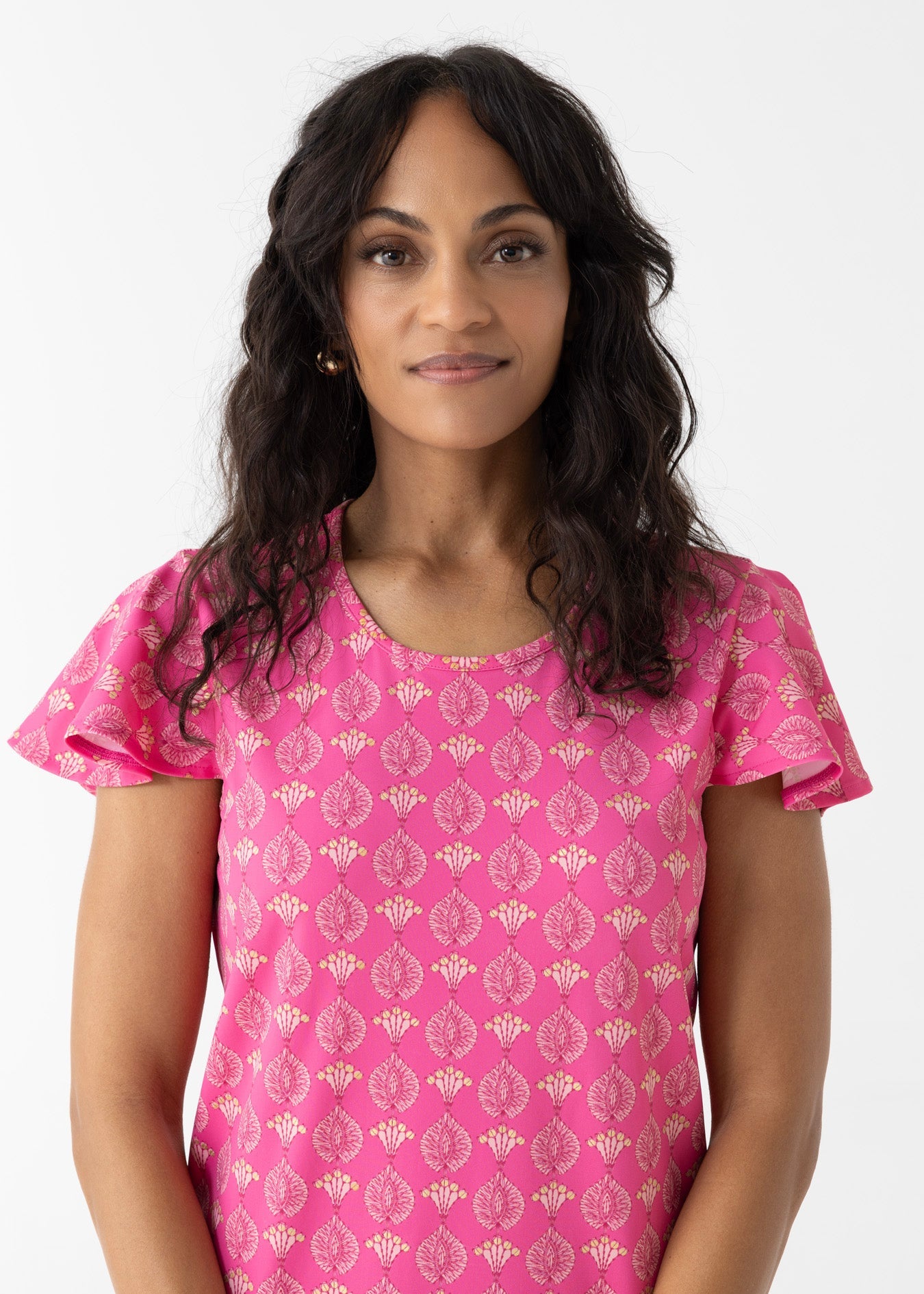Woman wearing a pink patterned top against a white background