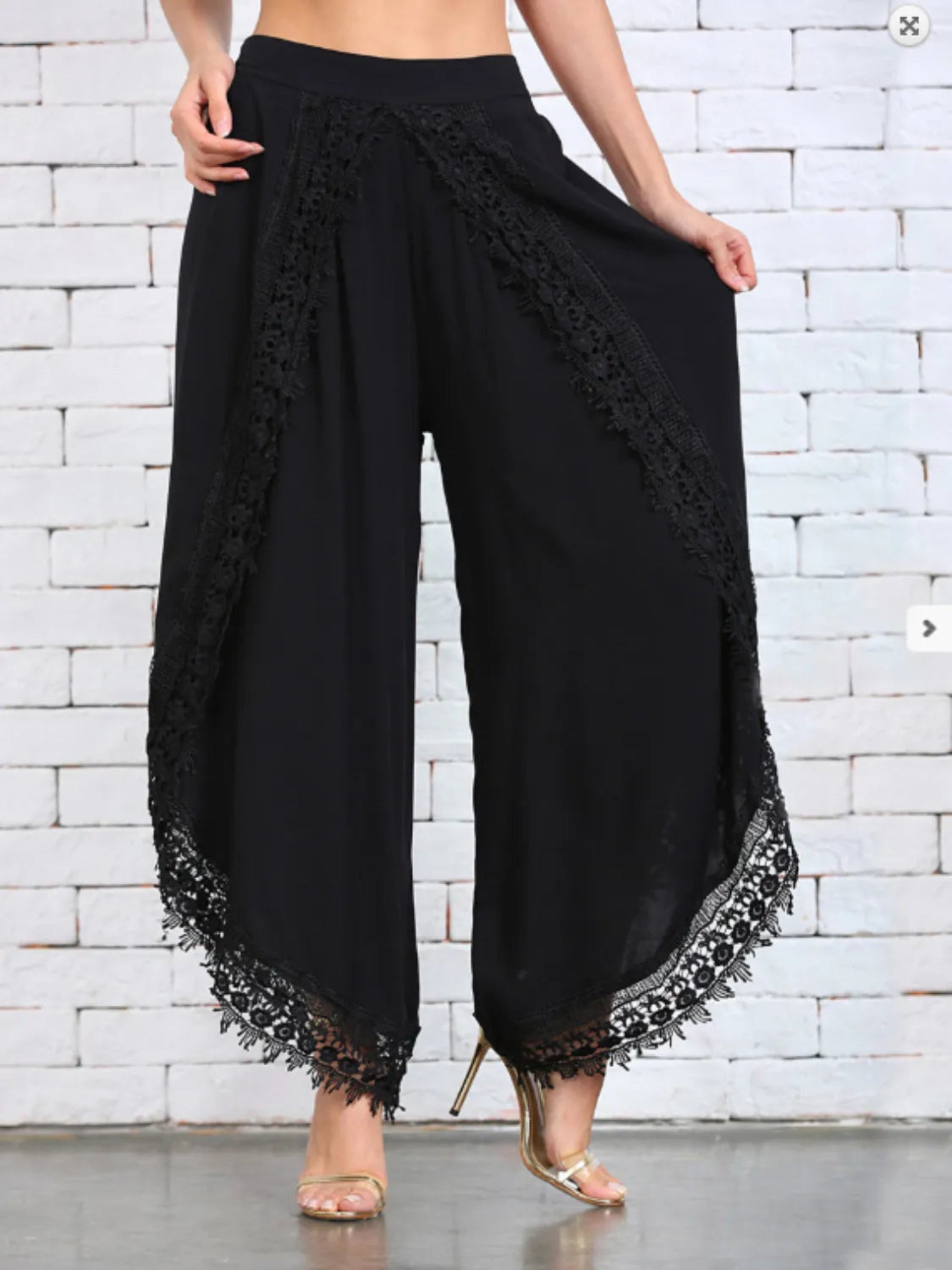 White wide leg pants with lace detailing at the hem, shown on a model wearing high heels.
