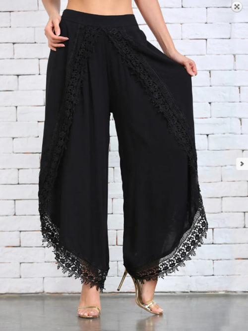 White wide leg pants with lace detailing at the hem, shown on a model wearing high heels.