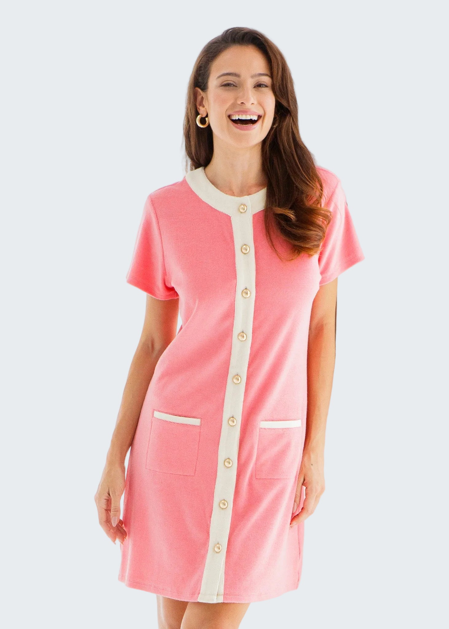 Woman wearing a pink dress with white accents standing in a bright room.