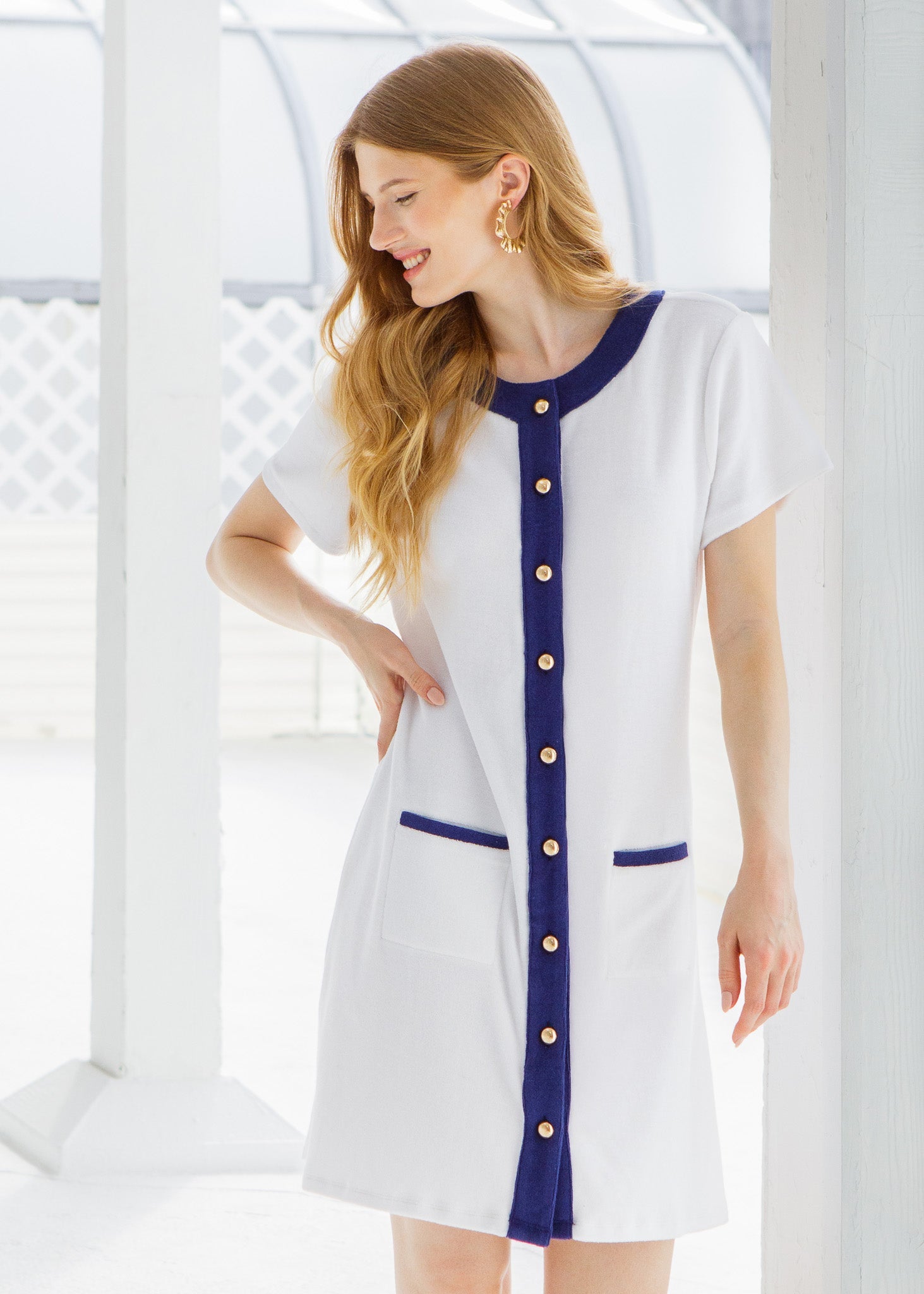 Woman wearing a white dress with blue accents and buttons in a bright setting