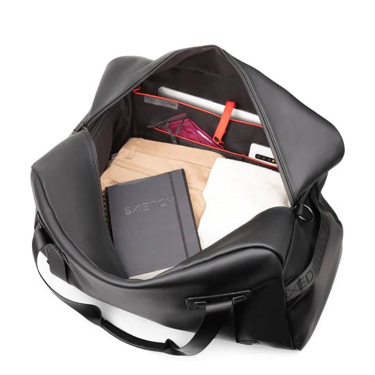 Black backpack with items including a notebook and a tablet inside on a white background