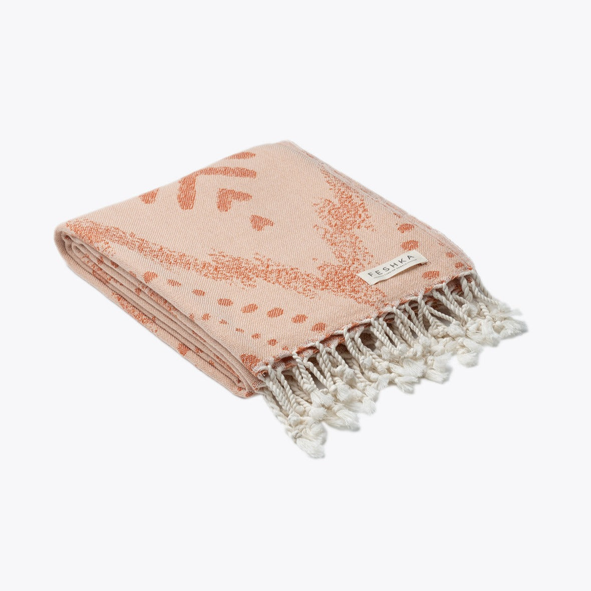 Folded pink towel with white fringe on a white background