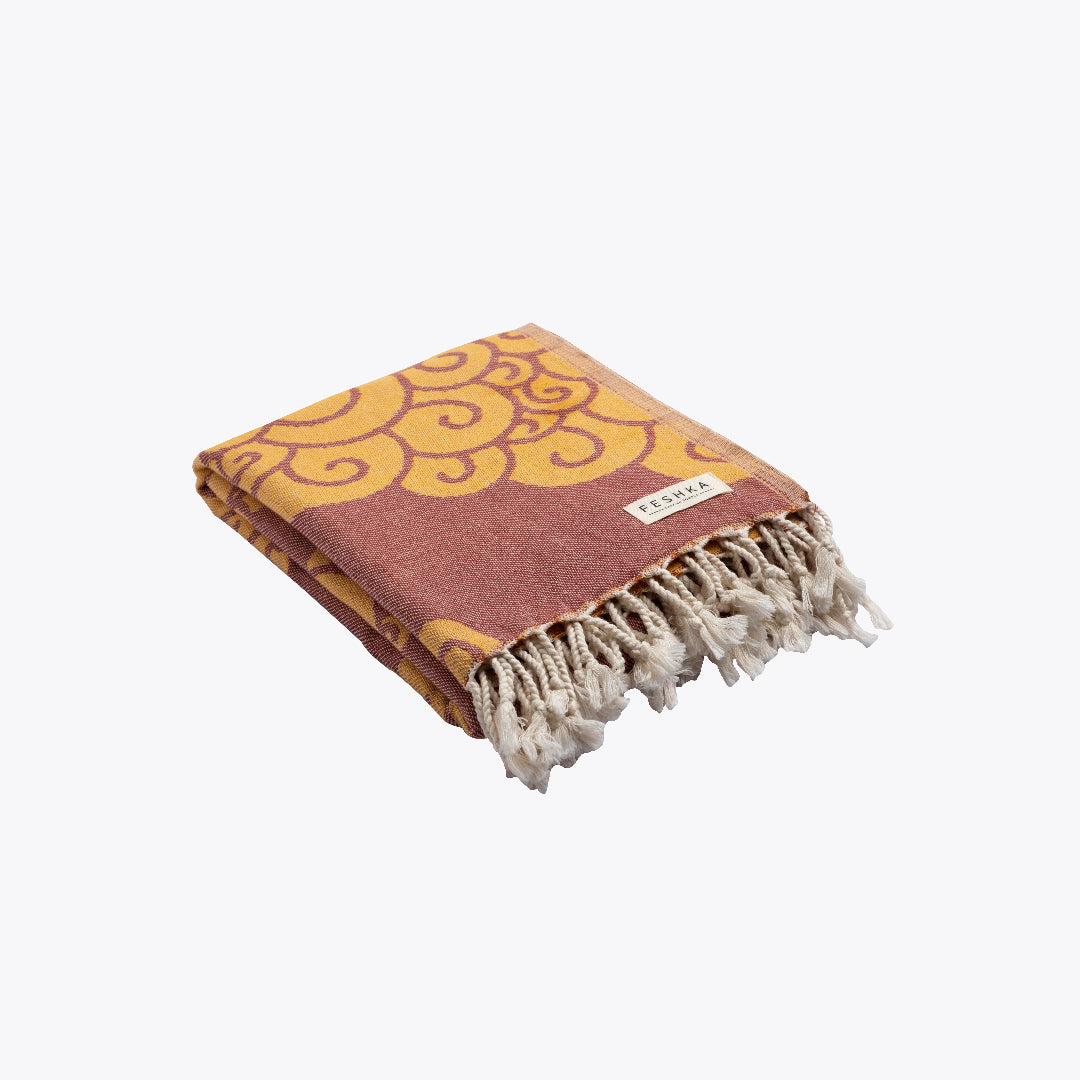 Folded towel with yellow pattern and fringed edge on a white background