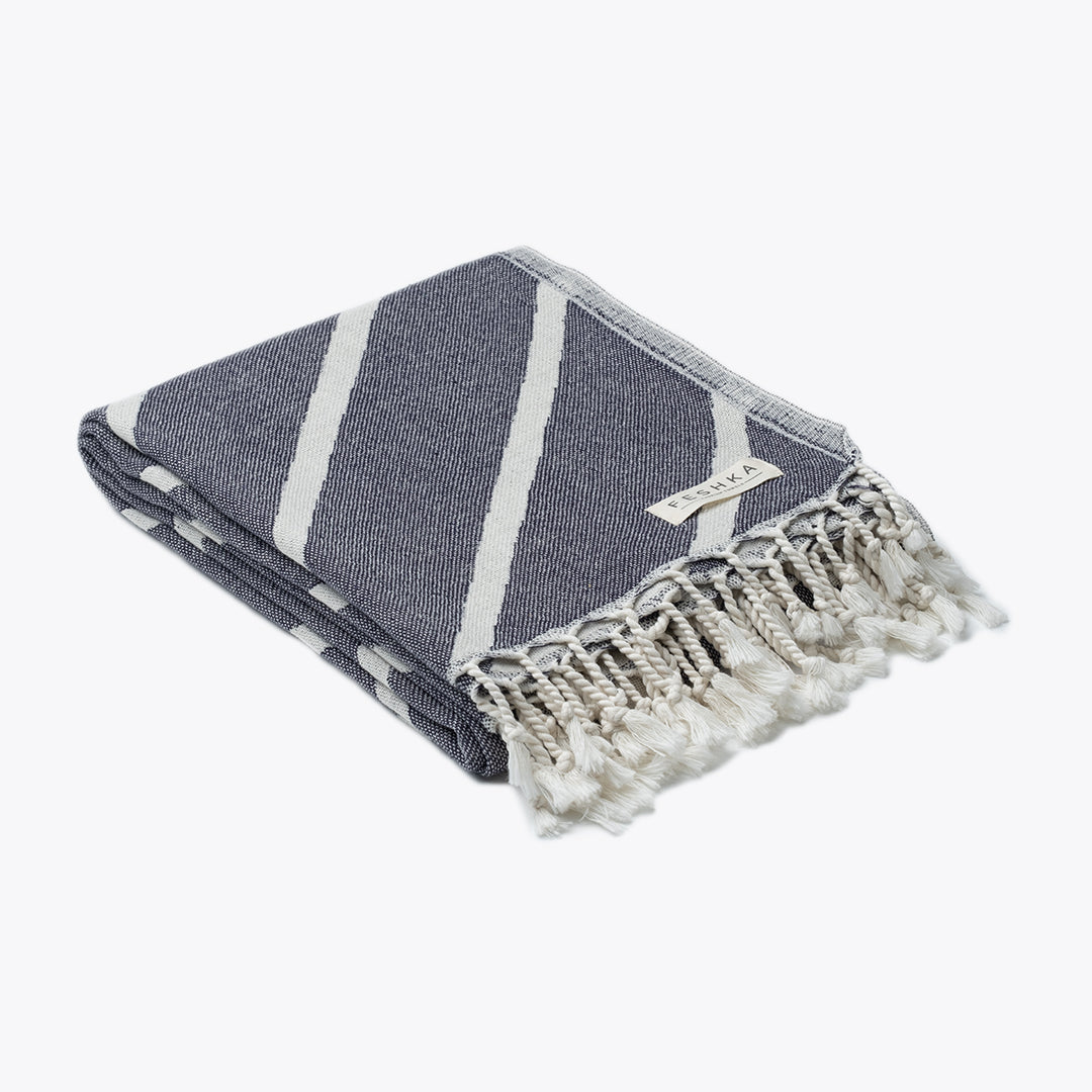 Gray and white striped towel with tassels on a white background