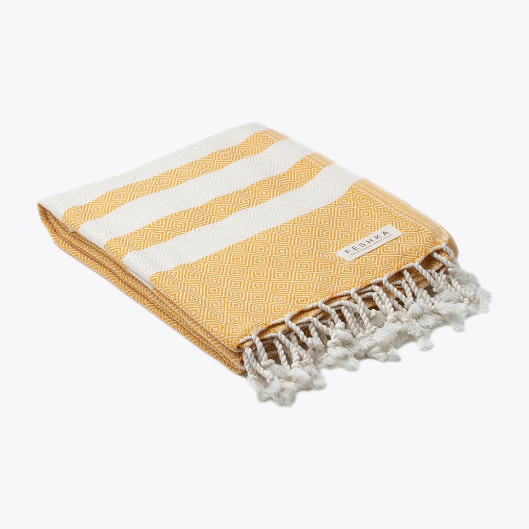 Yellow and white striped towel with fringes on a white background